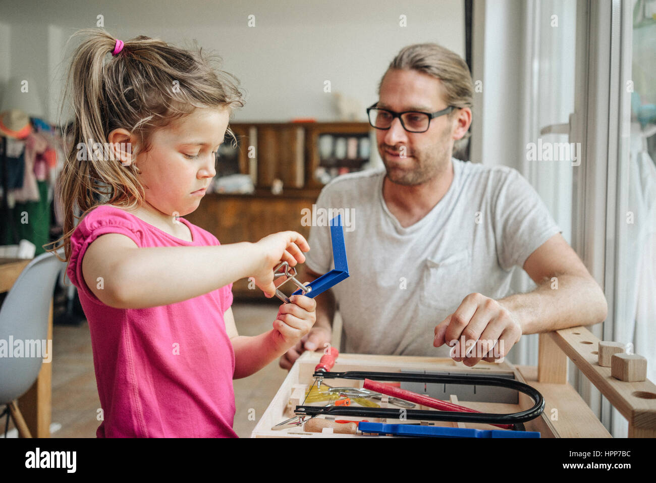 Father looking at daughter working with tools Stock Photo