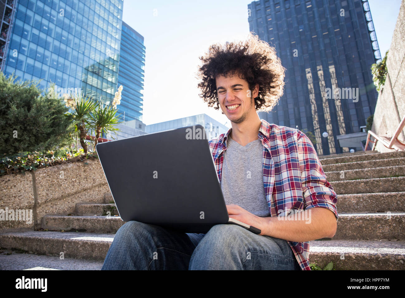 Portrait of young man sitting on stairs using laptop Stock Photo