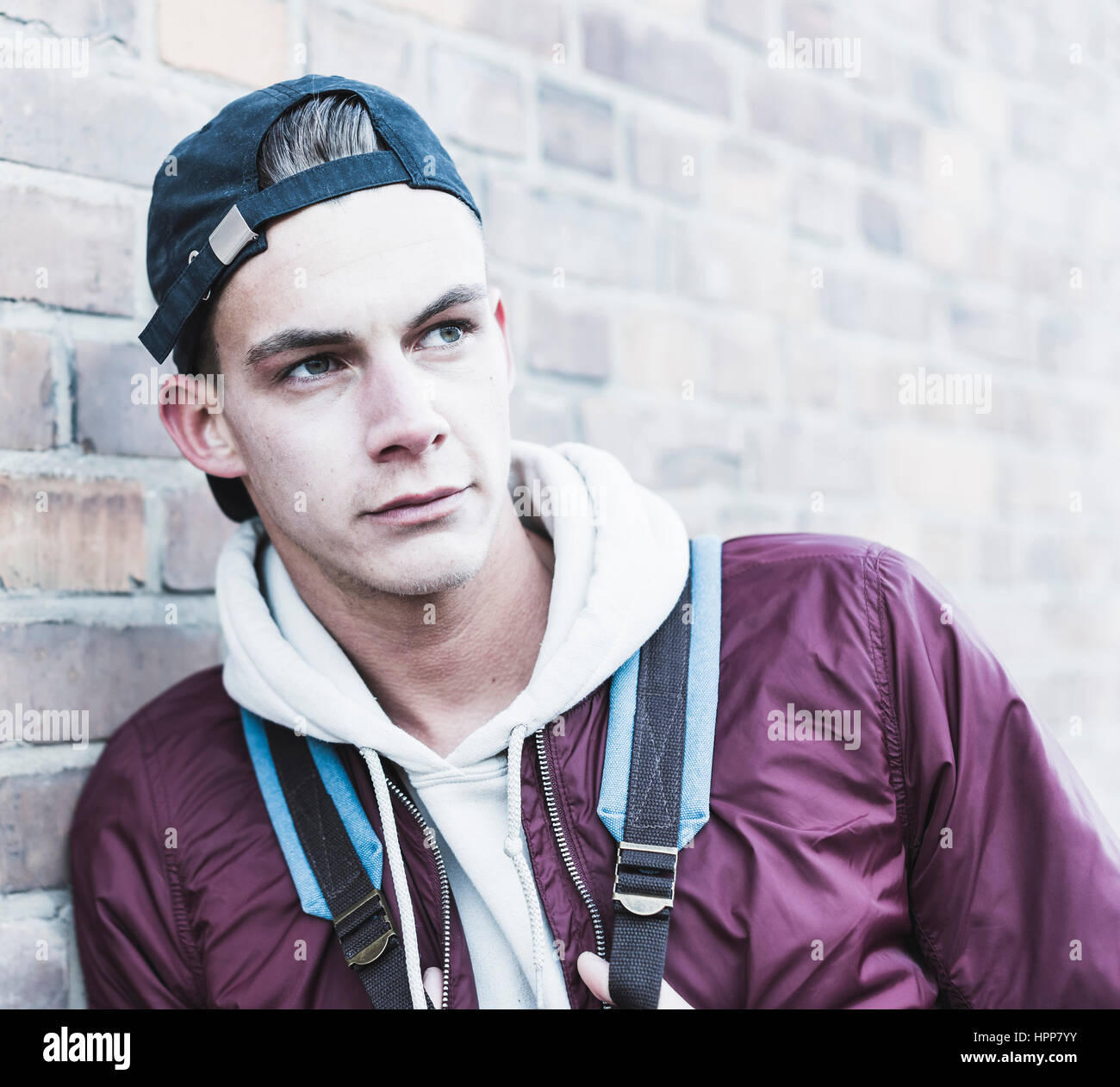 Portrait of young man leaning against brick wall Stock Photo - Alamy