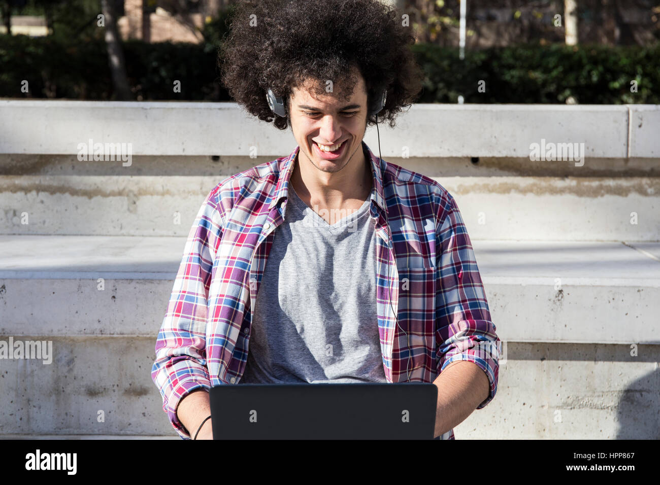 Smiling young man using laptop and headphones Stock Photo