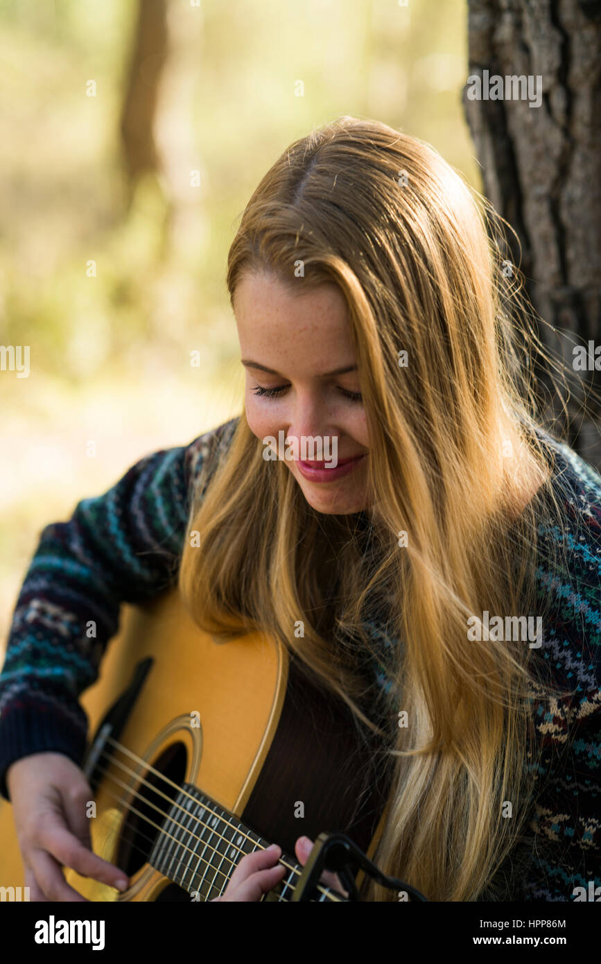 Smiling young woman playing guitar in nature Stock Photo - Alamy
