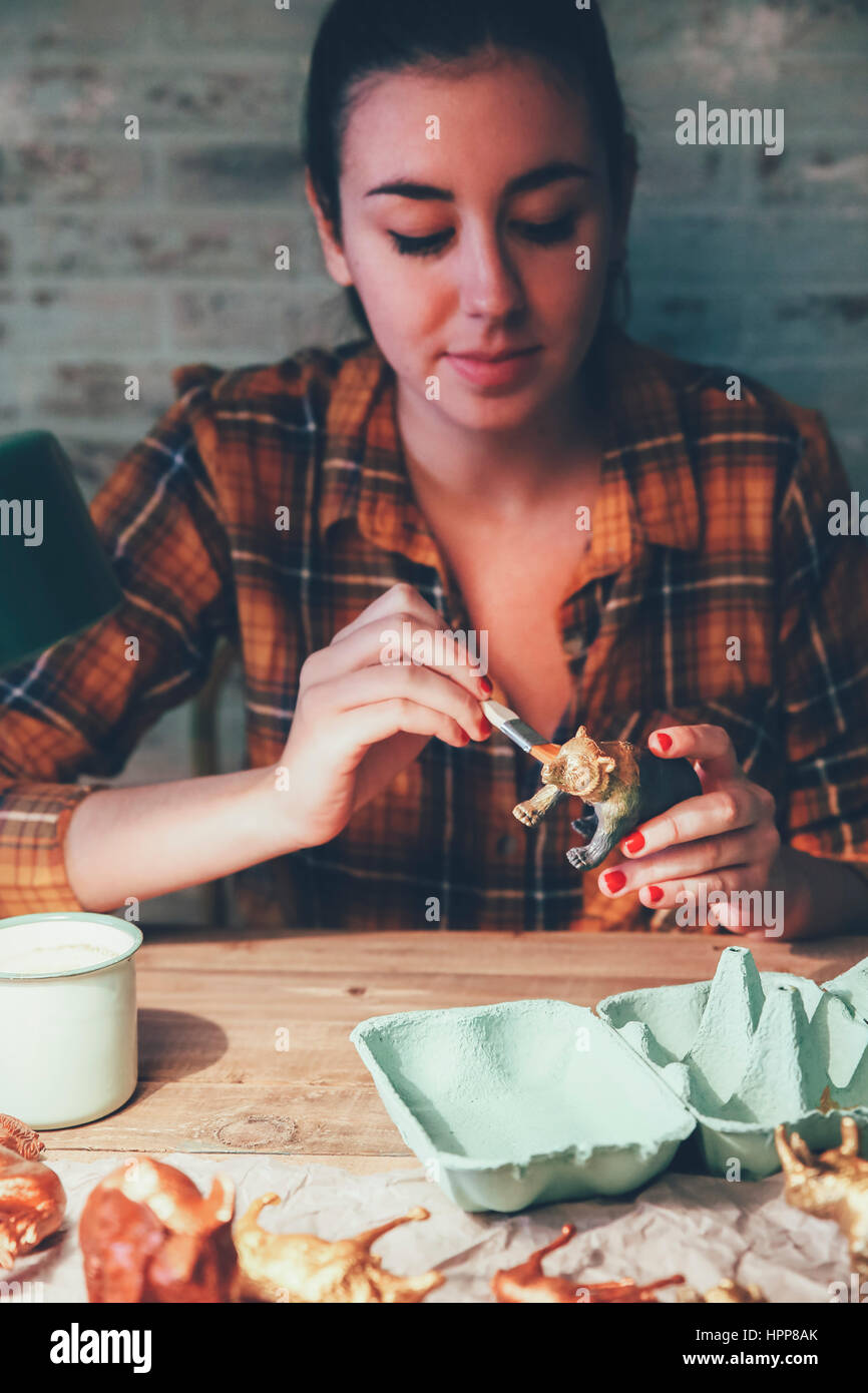Young woman painting bear plastic figure with gold paint Stock Photo