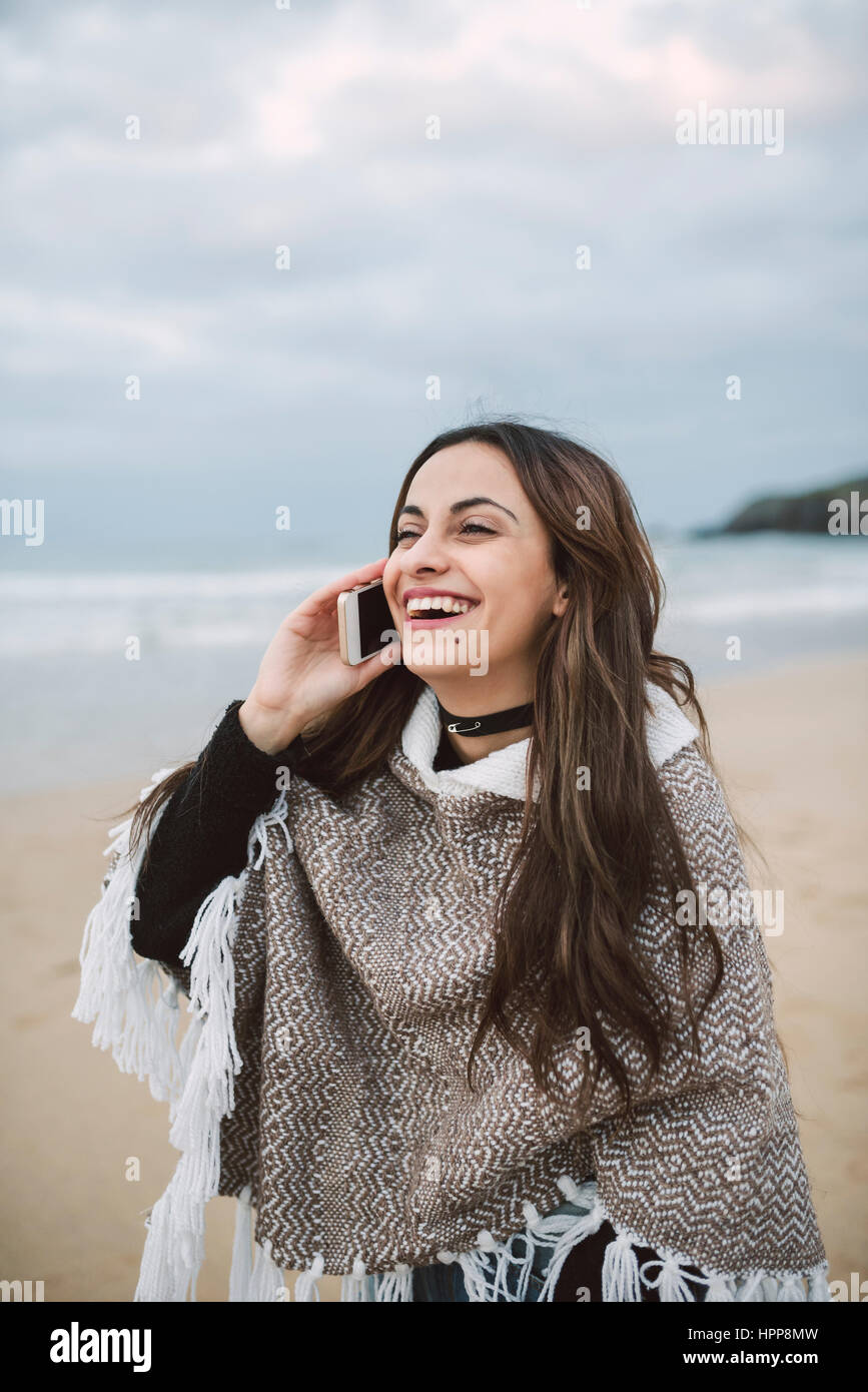 Portrait of happy young woman on the phone on  the beach Stock Photo