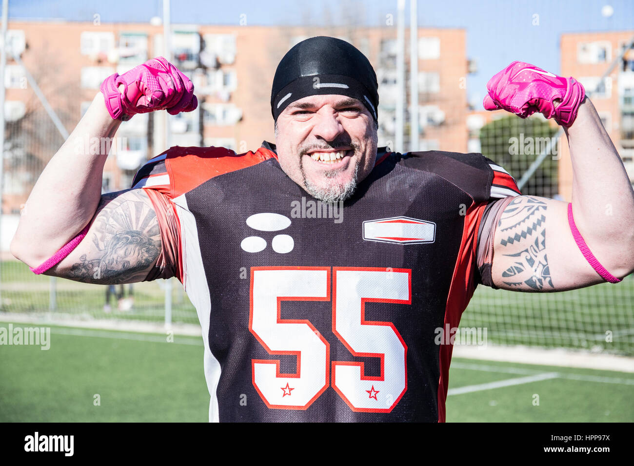 Portrait of confident American football player flexing his muscles ...