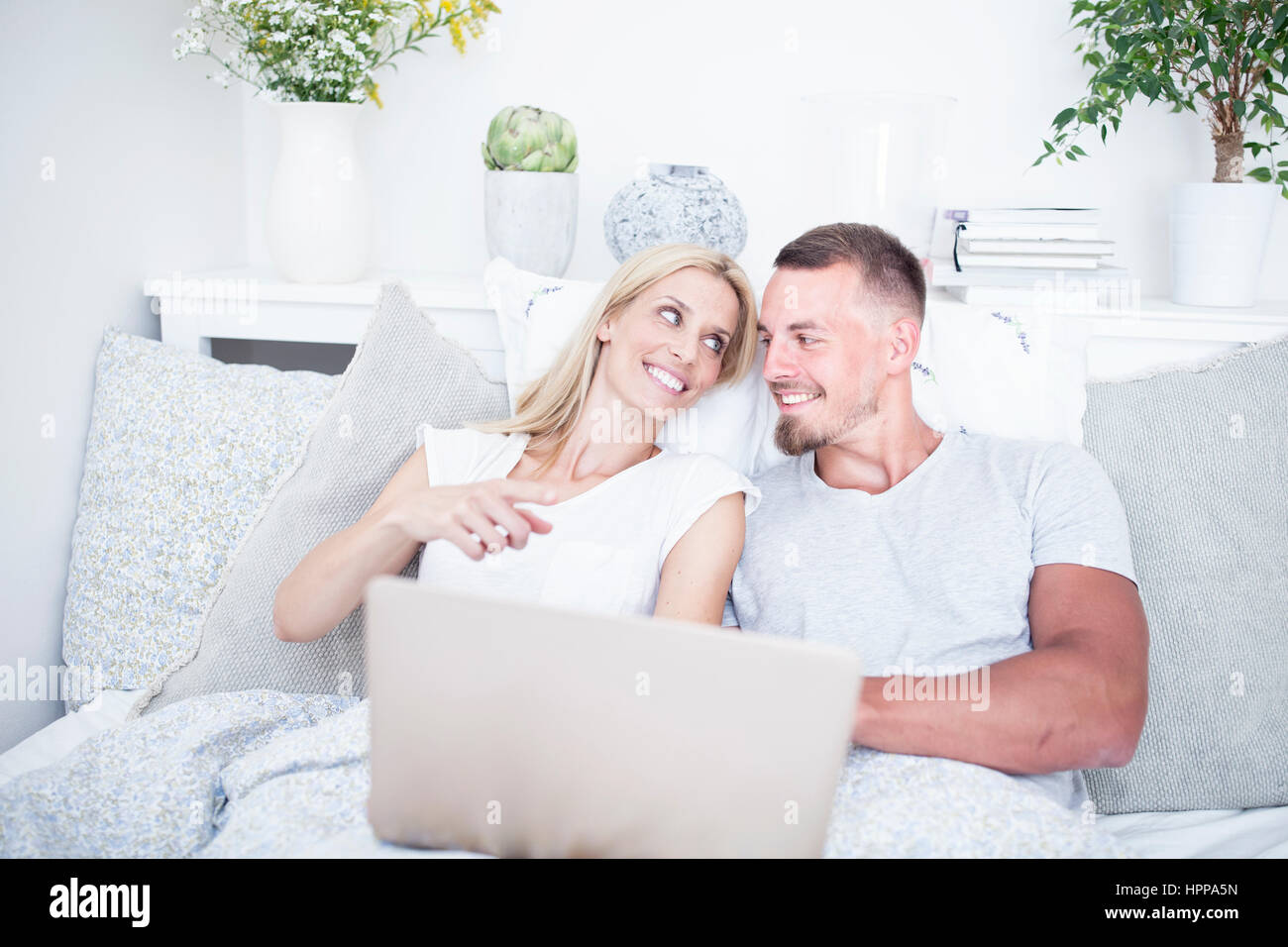 Relaxed couple in bed using laptop Stock Photo - Alamy