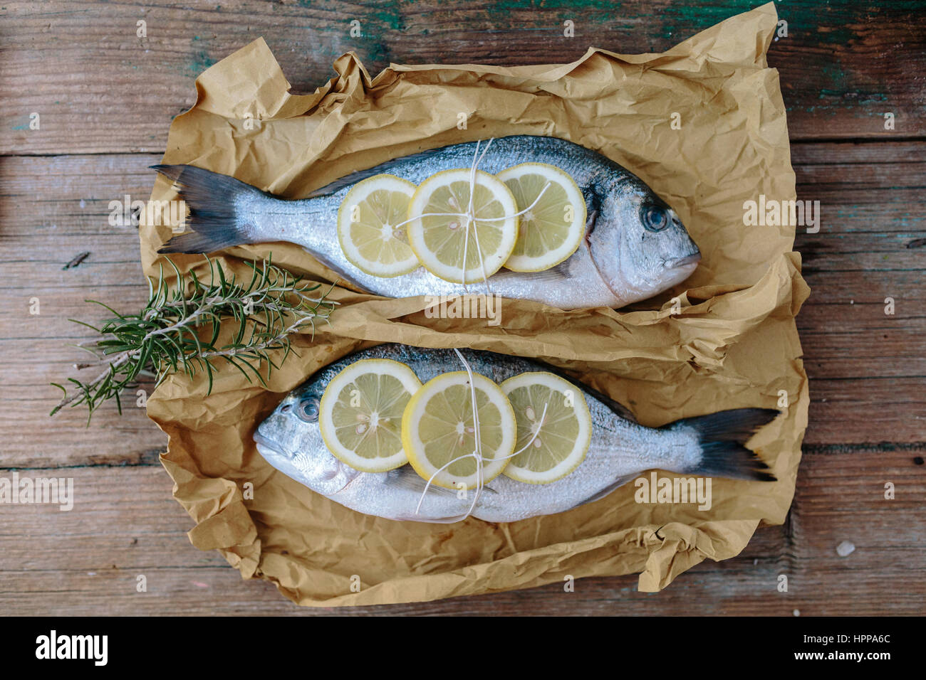 Two Sea Bream on a baking paper with lemon and rosemary Stock Photo Alamy