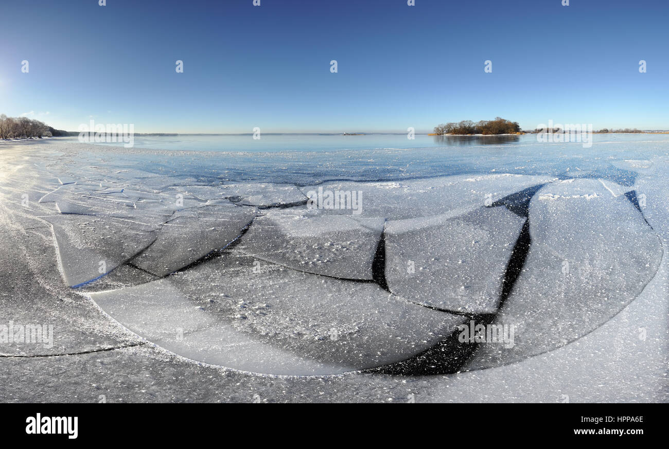 Bay covered  by thin crystal ice. Sunny winter morning. Blue sky above lake. Stock Photo