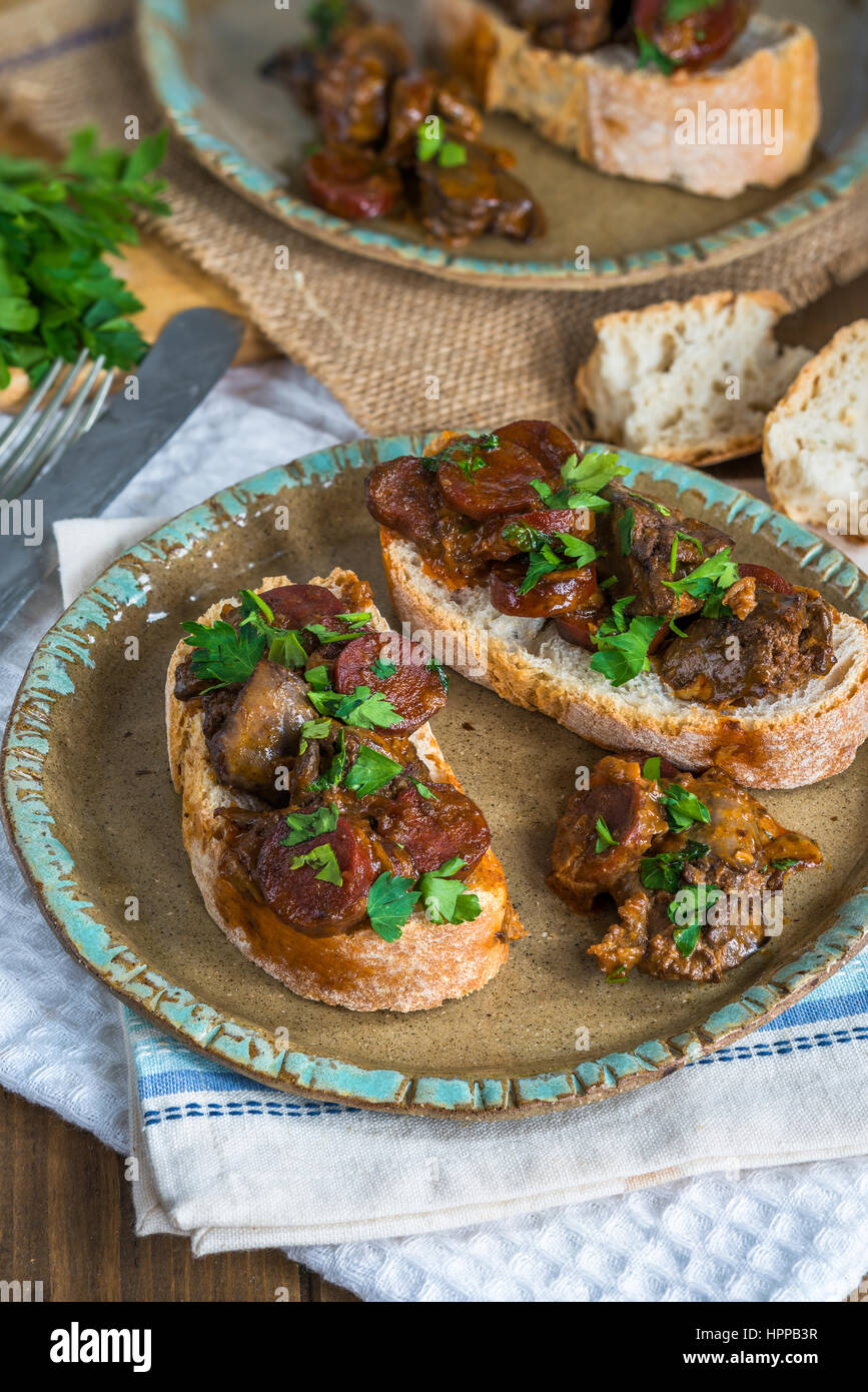 Chicken liver and chorizo open sandwich garnished with fresh parsley
