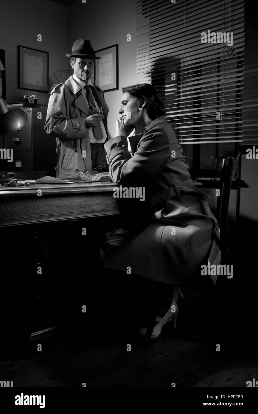 Detective interviewing a young sad woman in his office, film noir scene. Stock Photo