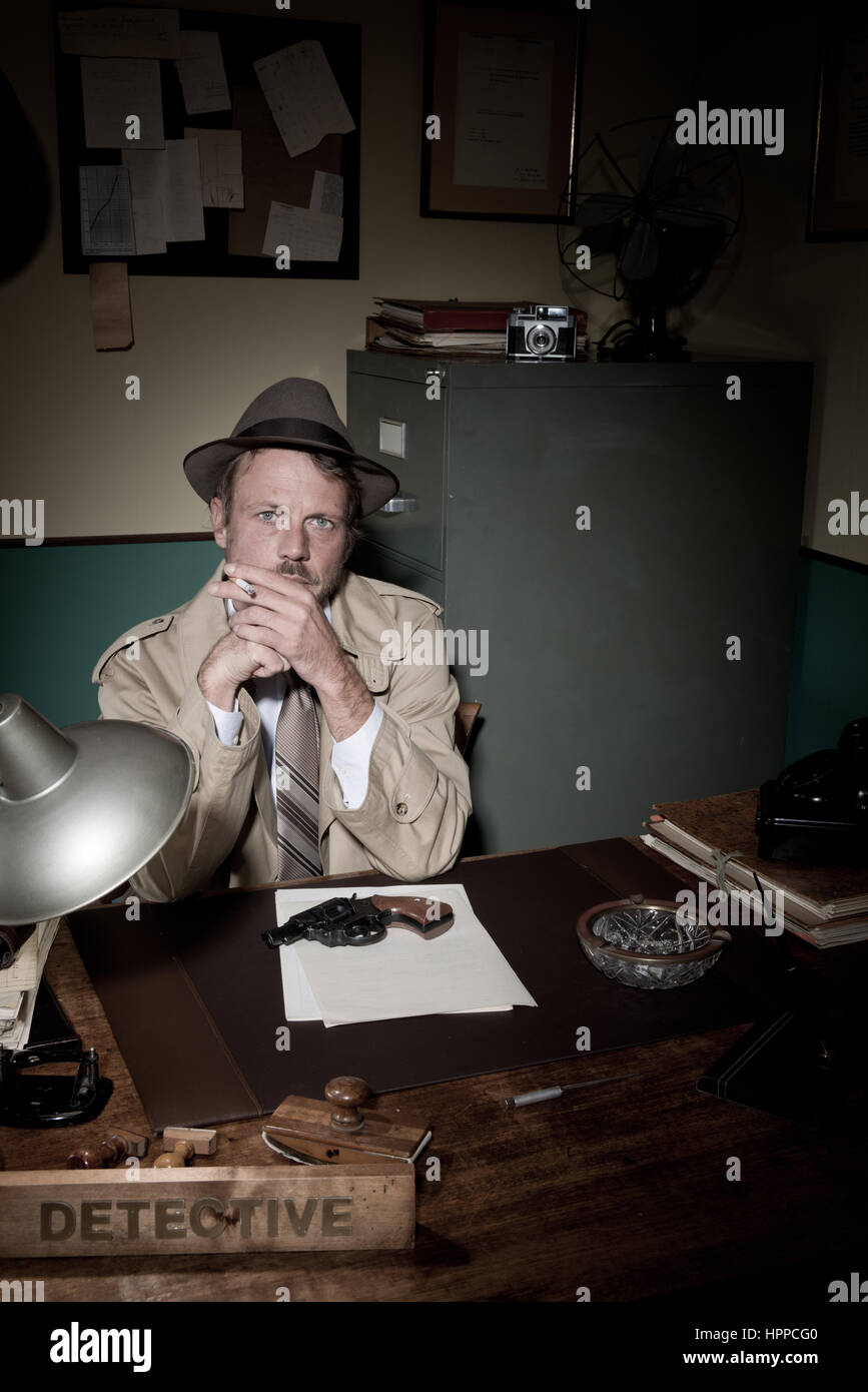 Confident detective smoking at desk in trench coat, 1950s film noir