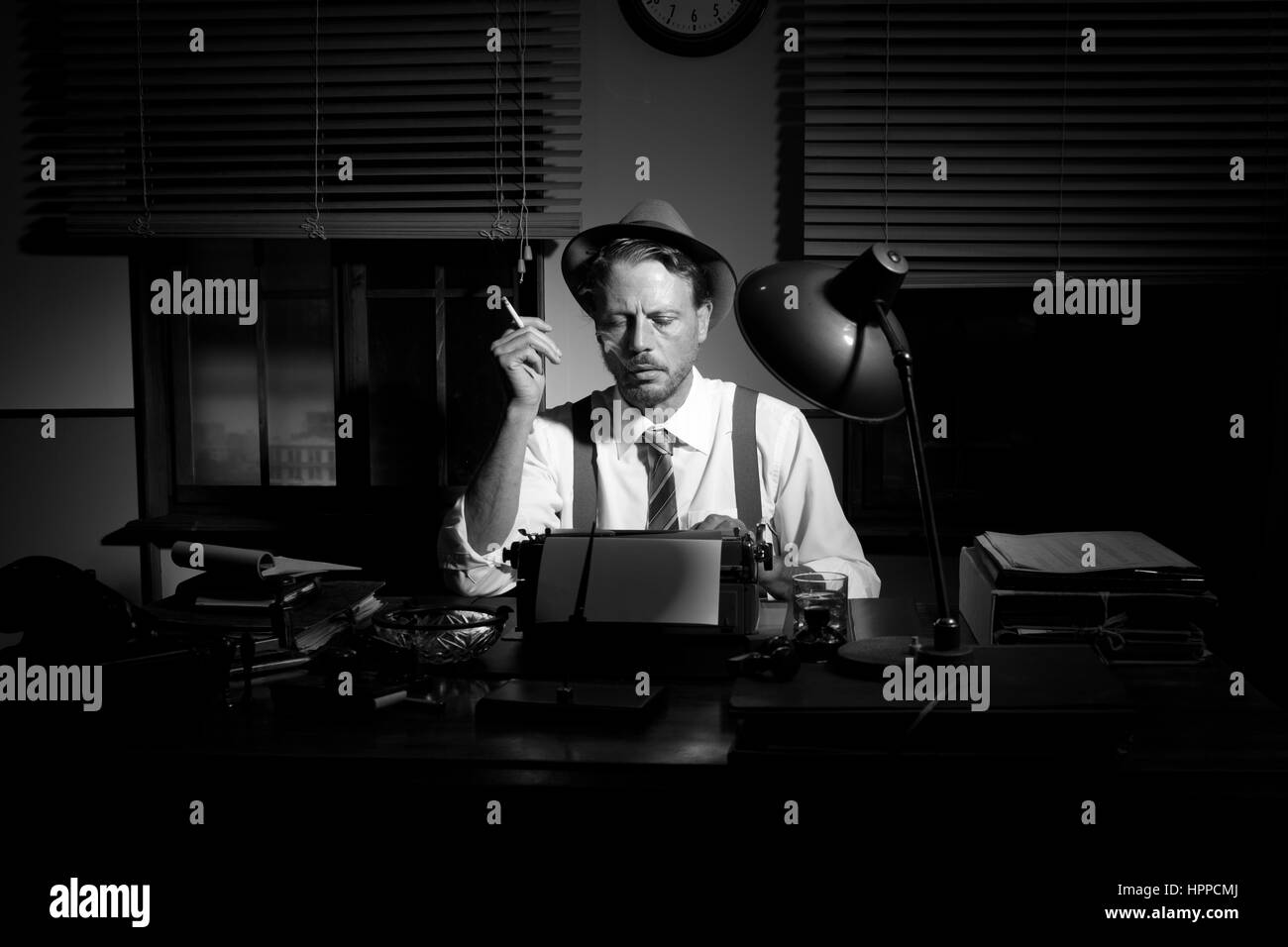 Retro reporter working late typing on a typewriter and smoking a ...