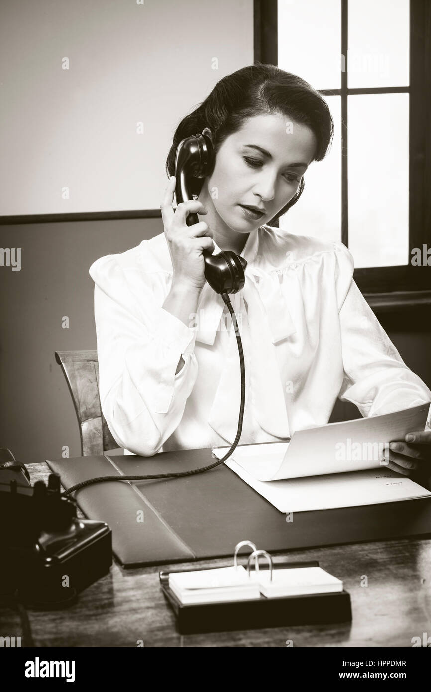 Attractive vintage secretary working at desk and having a phone