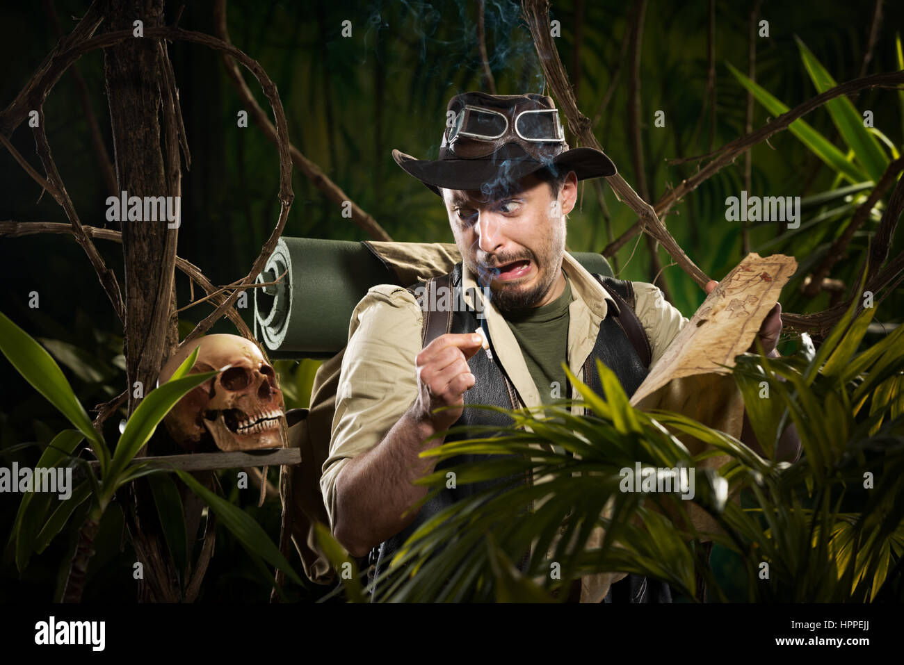 Explorer with map smoking in the jungle and finding a human skull. Stock Photo