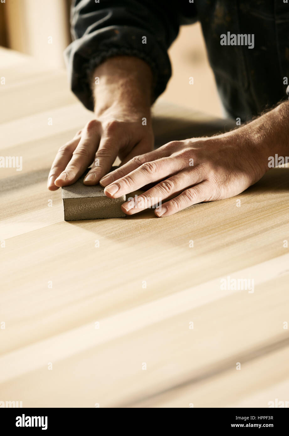 Professional carpenter sanding and refinishing wood surface Stock Photo