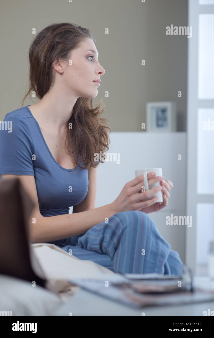 Young woman holding a cup of coffee in bed Stock Photo - Alamy