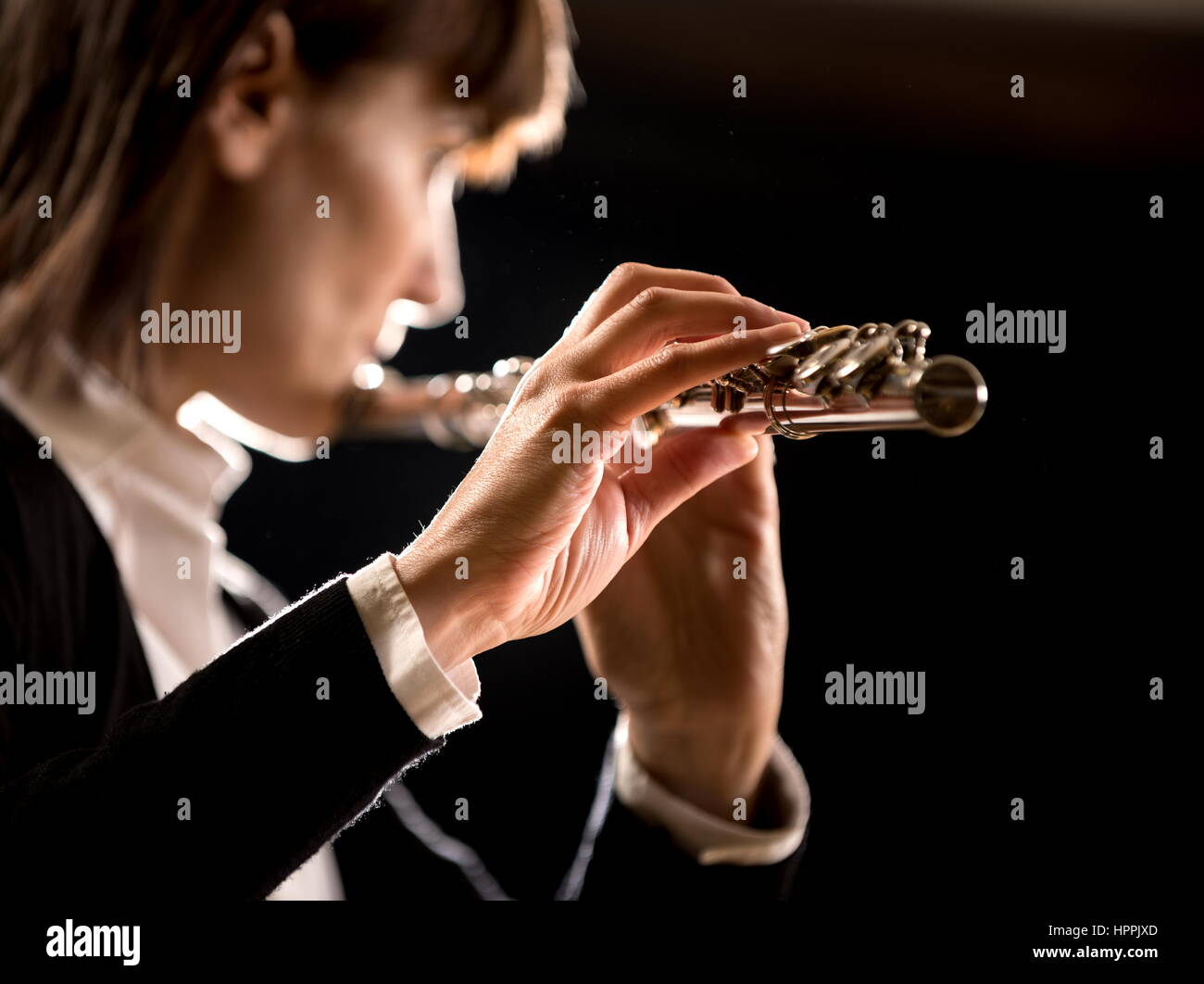 Elegant female flutist playing flute hires stock photography and