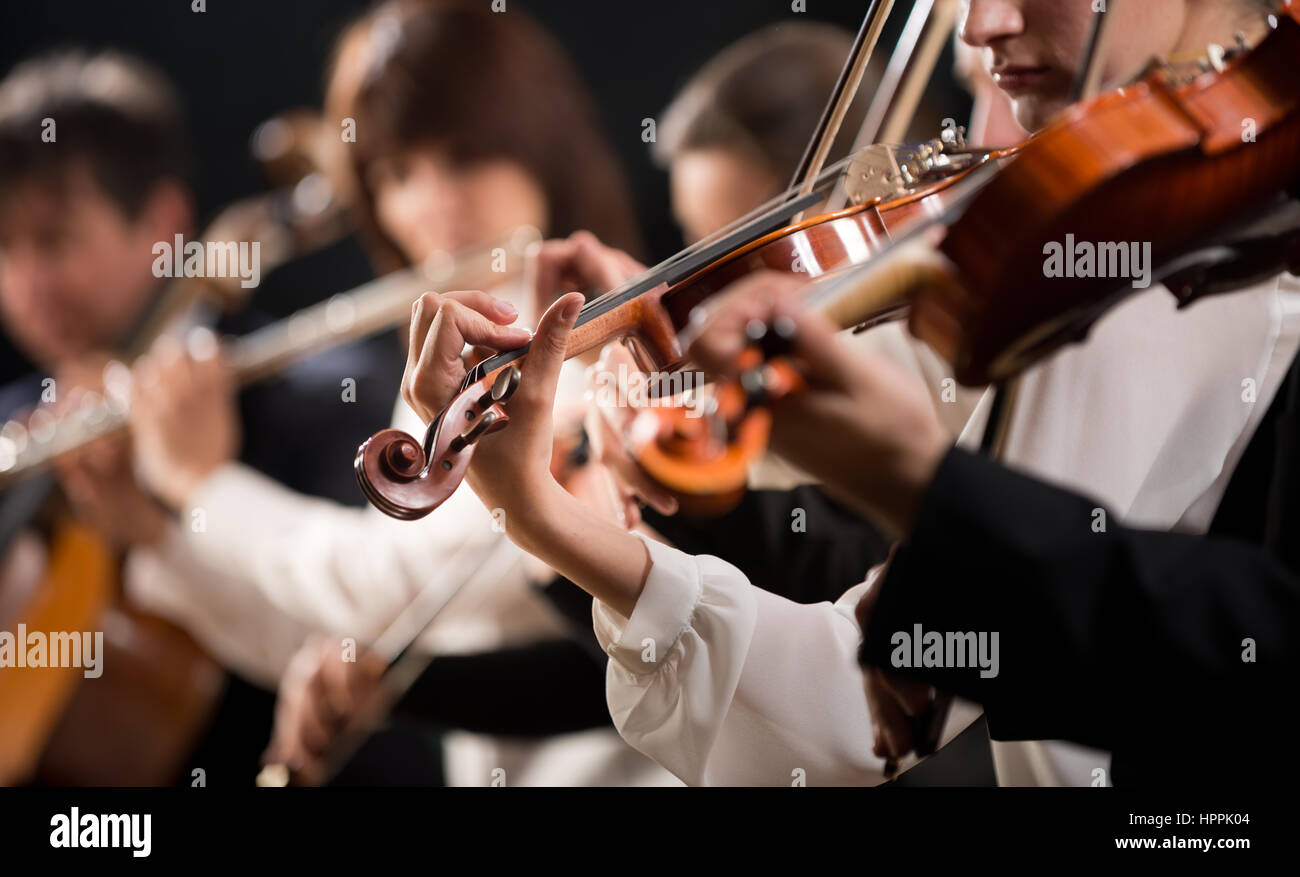 Symphony orchestra first violin section performing on dark