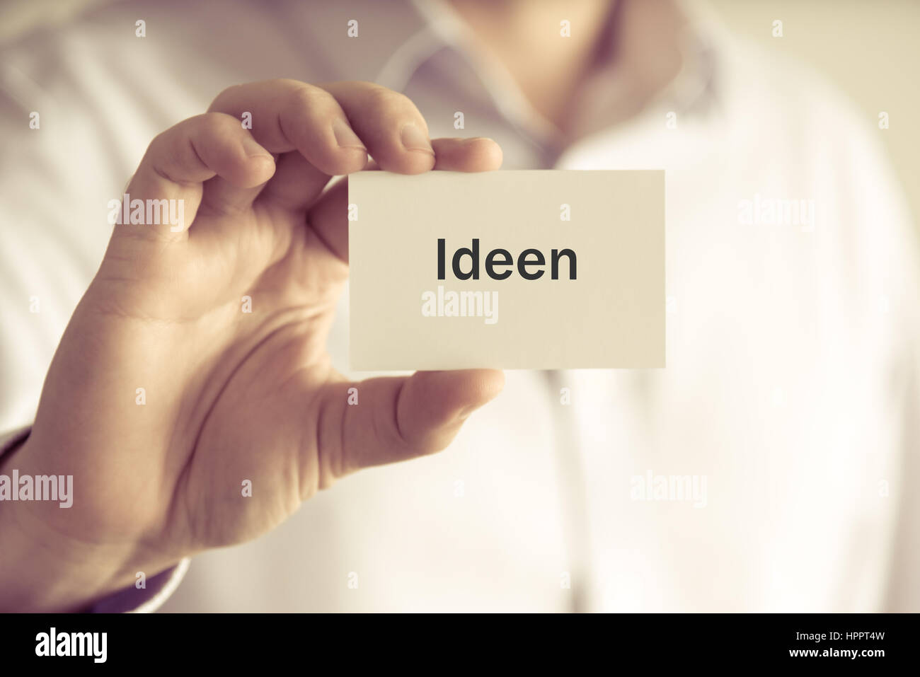 Closeup on businessman holding message card 'IDEEN' written in German - translation : IDEA, business concept image with soft focus background and vint Stock Photo