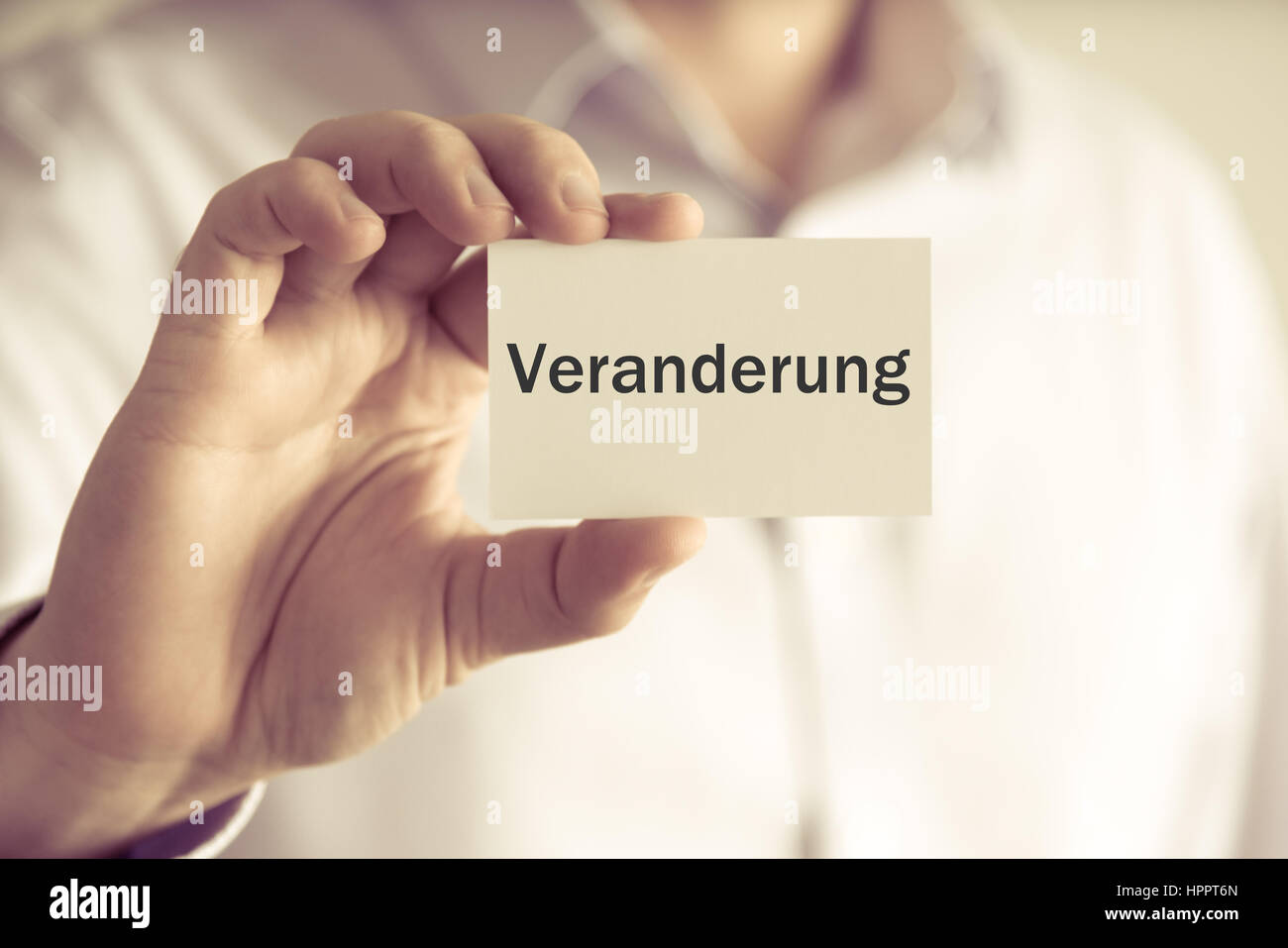Closeup on businessman holding message card 'Veranderung' written in German - translation : Change, business concept image with soft focus background  Stock Photo