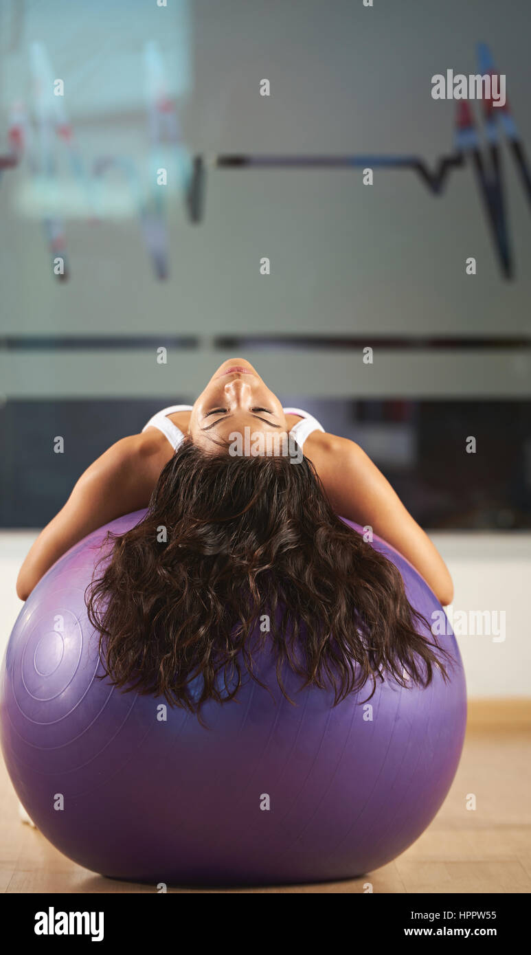 woman exercise with fitness ball in modern gym background. Sporty girl put her head on fitness ball Stock Photo