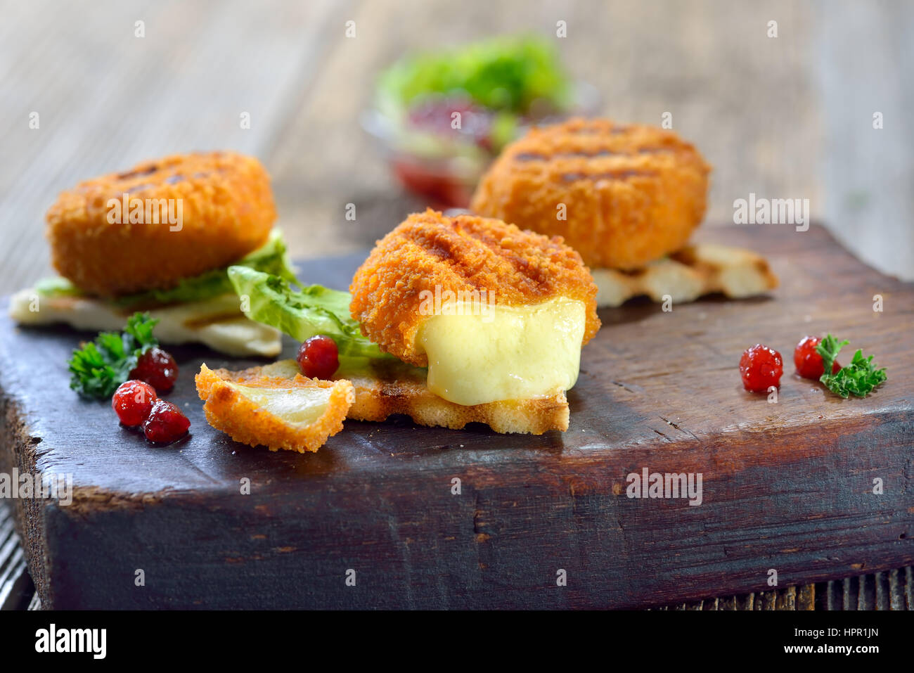 Toasted panini triangles with breaded mini camembert cheese loaves, cranberries and iceberg