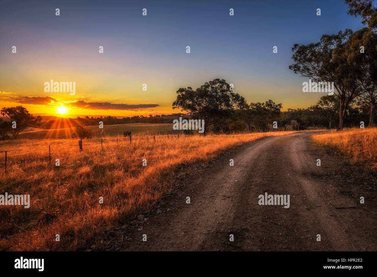 Scenic countryside landscape with rural dirt road at sunset in Australia Stock Photo