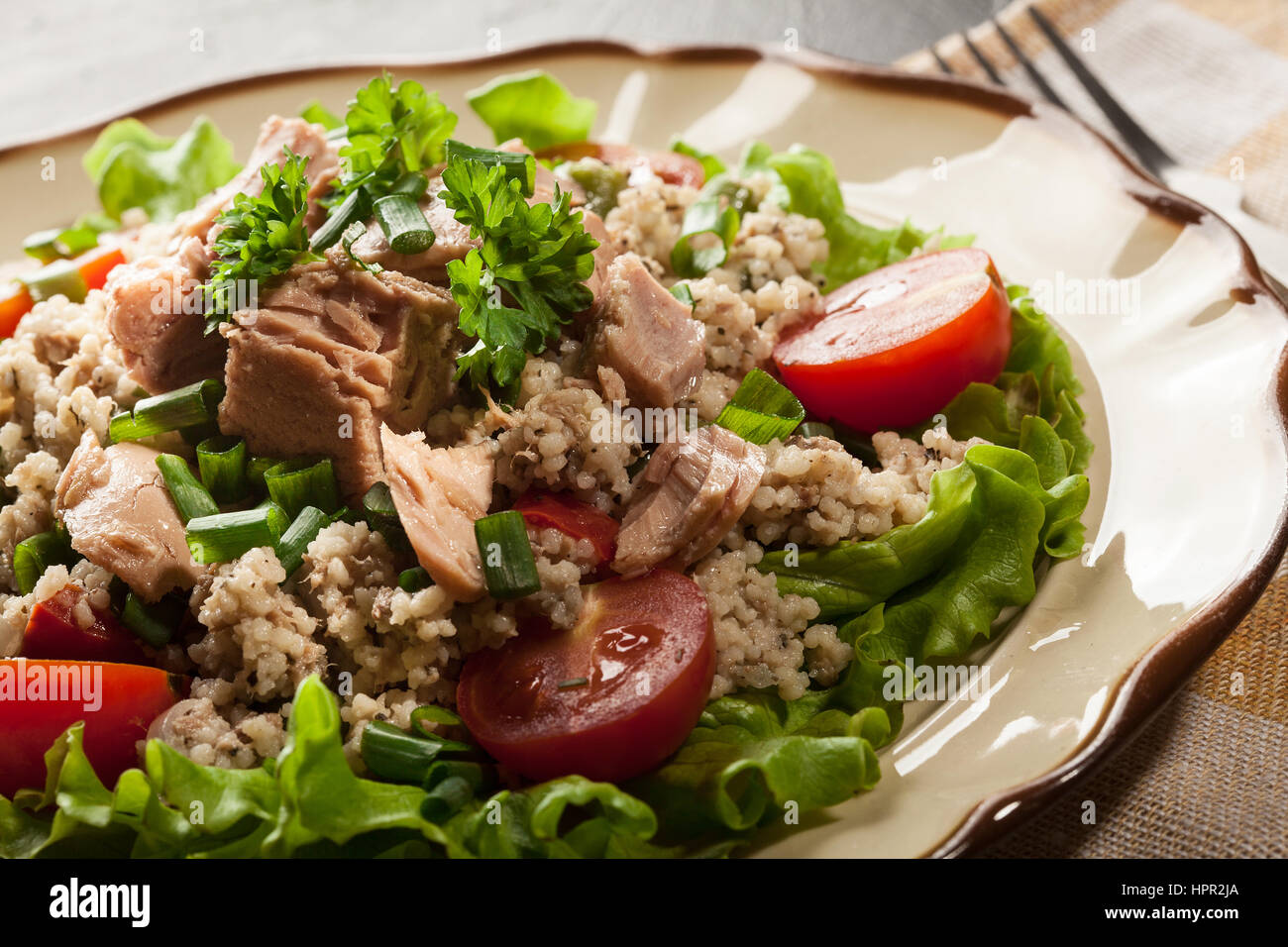 Tasty salad with couscous, tuna and vegetables on the plate Stock Photo