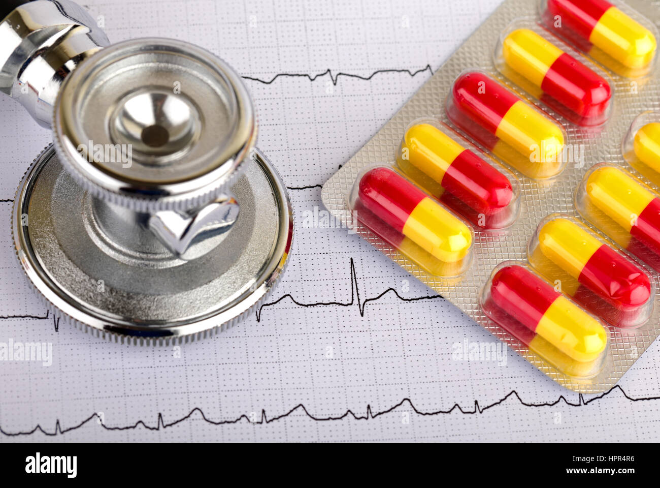 Electrocardiogram graph report with stethoscope and pills on it Stock Photo