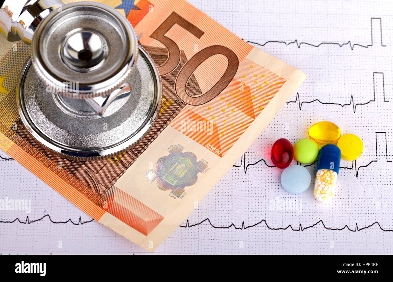 Stethoscope over electrocardiogram graph and 50 euro Stock Photo