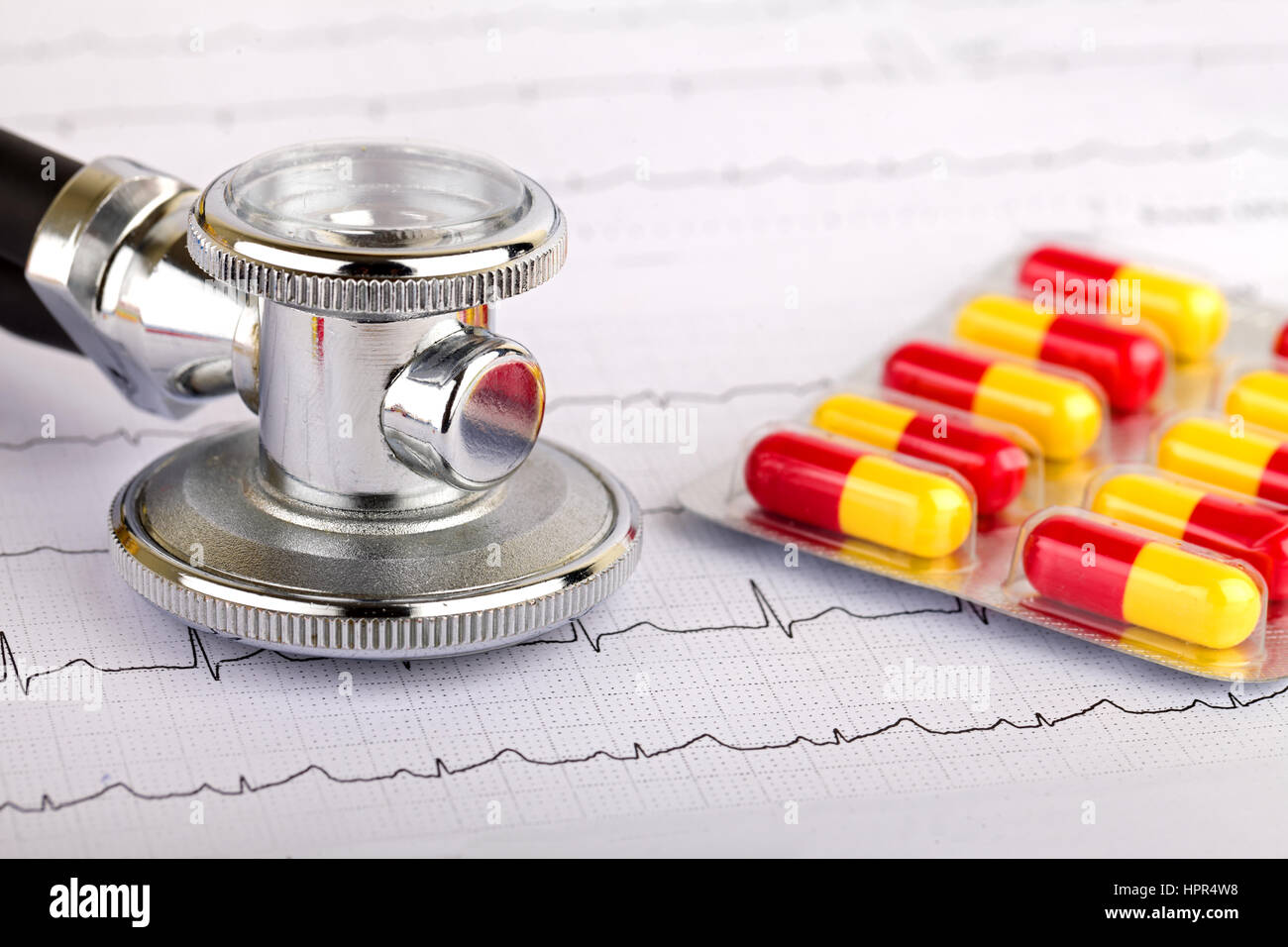 Electrocardiogram graph report with stethoscope and pills on it Stock Photo