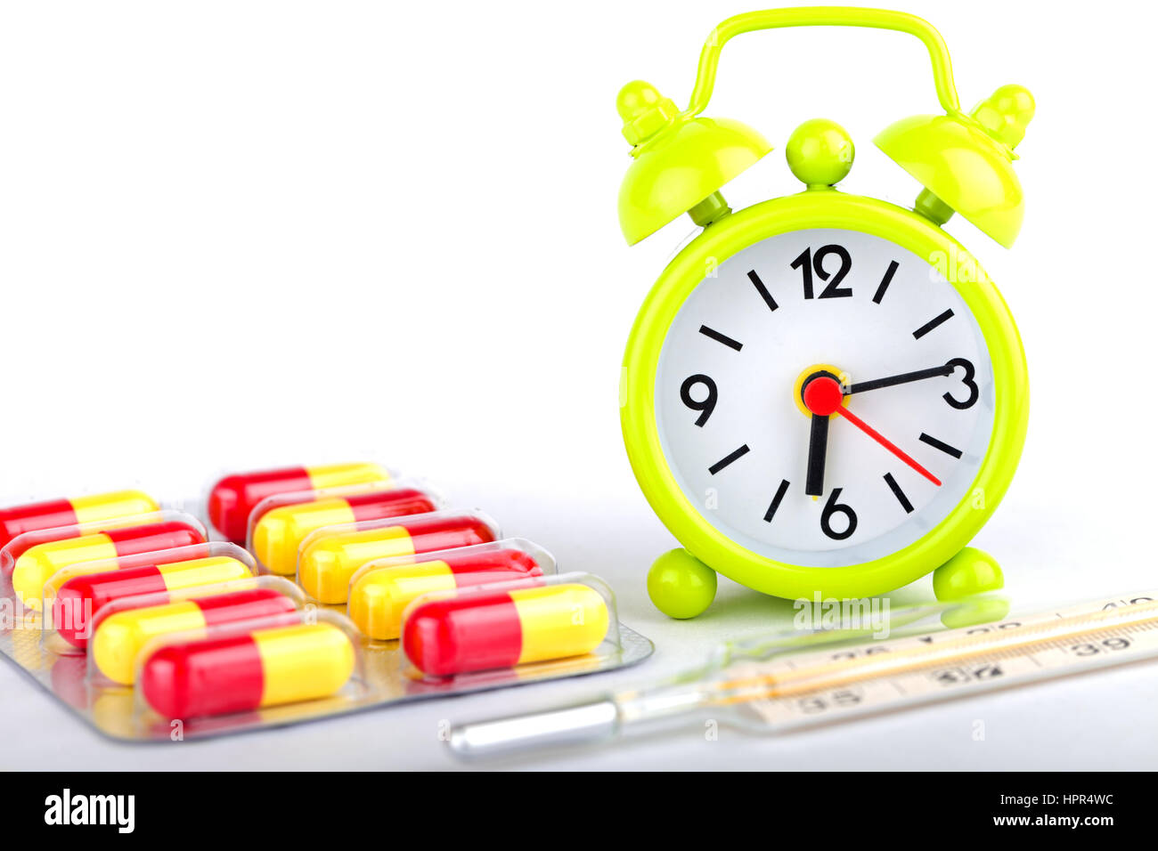 Picture of a green clock, colourful pills and capsules Stock Photo