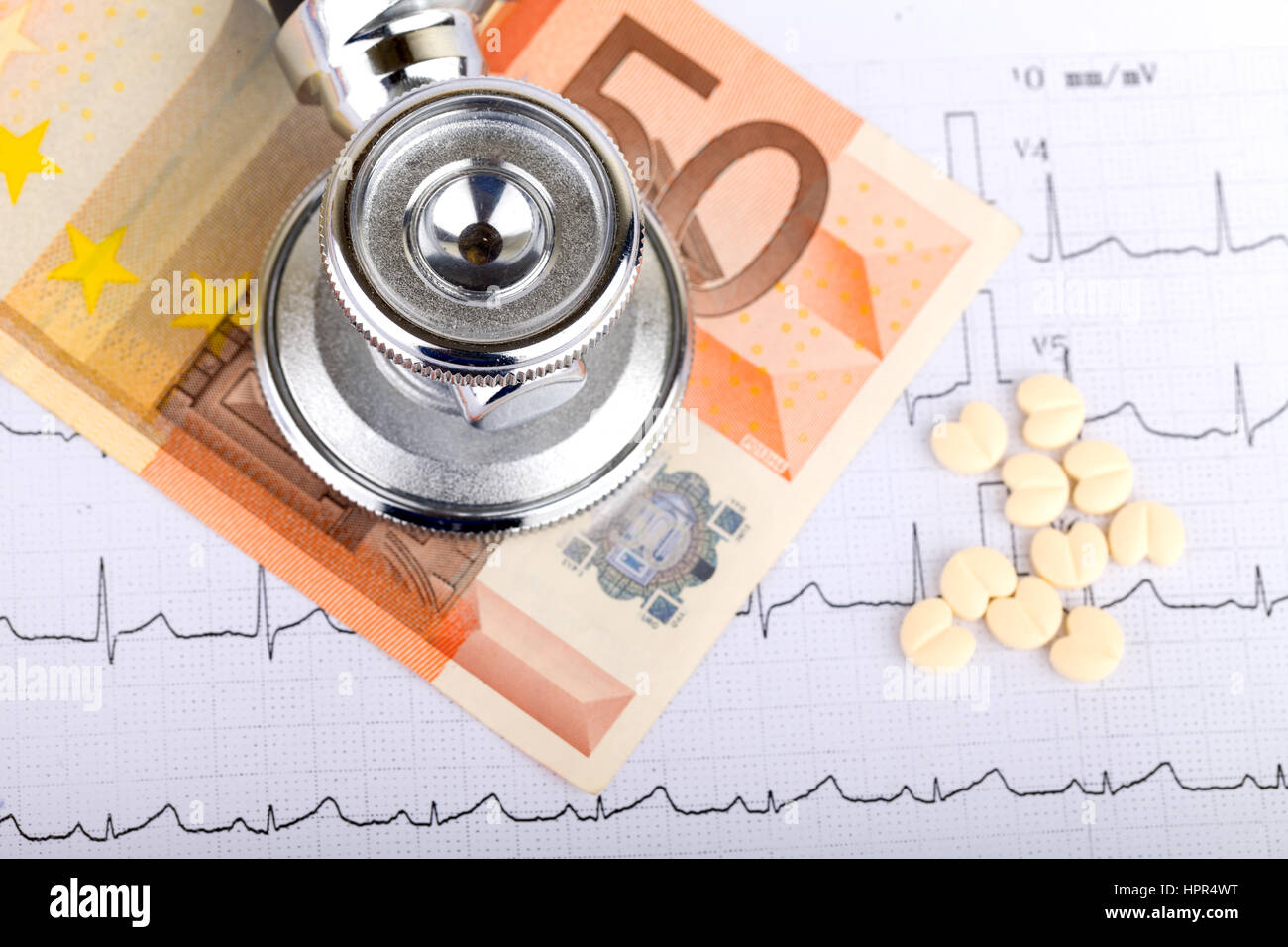 Stethoscope over electrocardiogram graph and 50 euro Stock Photo