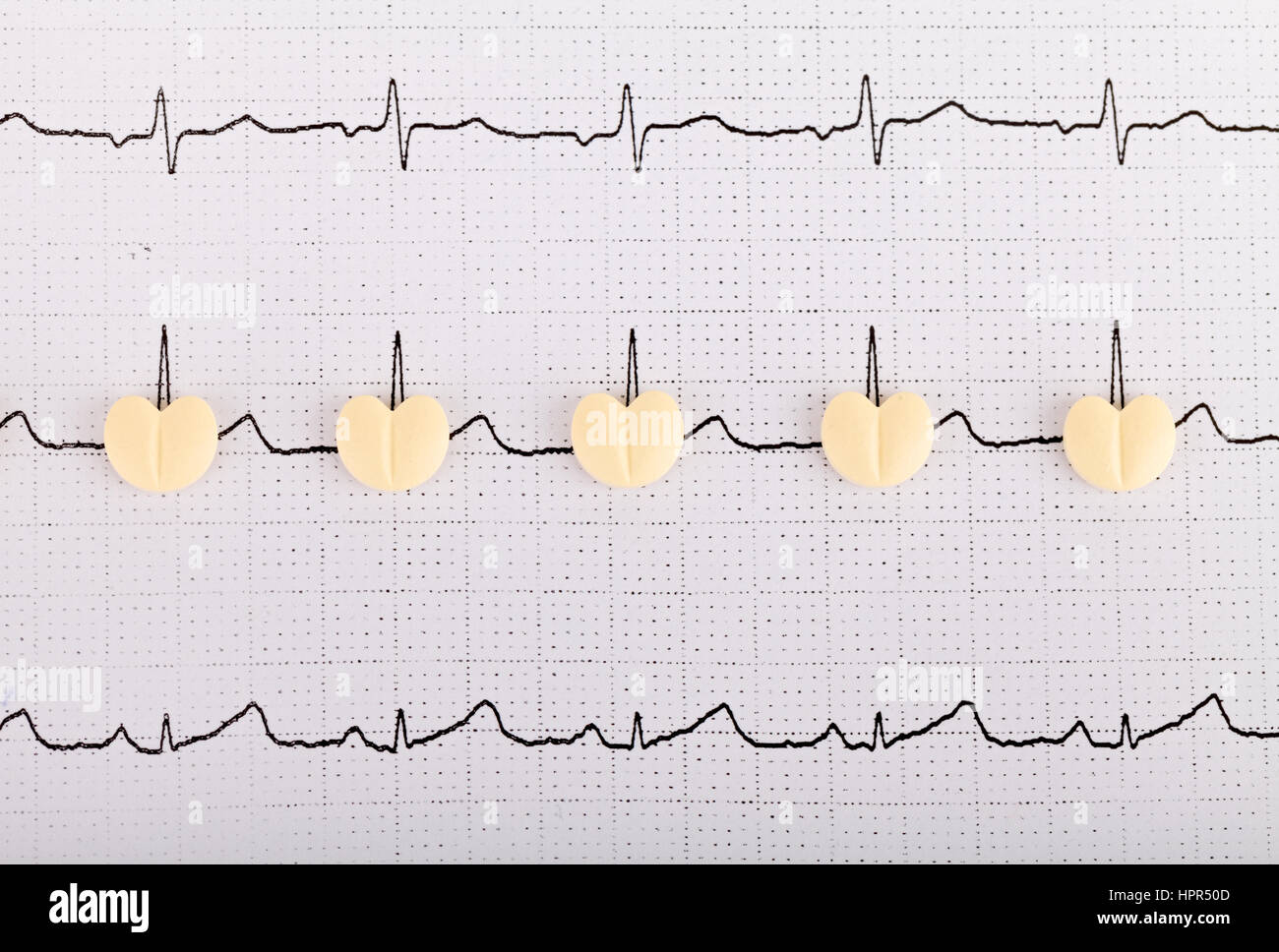 Electrocardiogram graph report with  heart shape pills on it Stock Photo