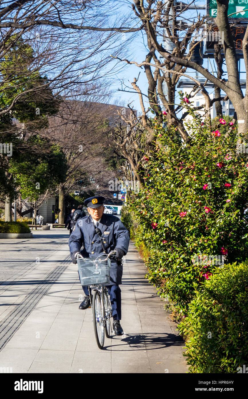 A security guard riding on a bicycle on the pavement outside the Tokyo
