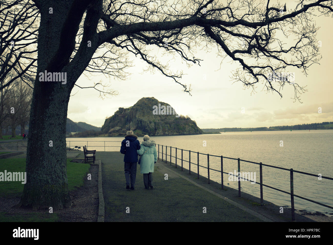 Dumbarton castle rock viewed from the shore at leven park old couple walking Stock Photo