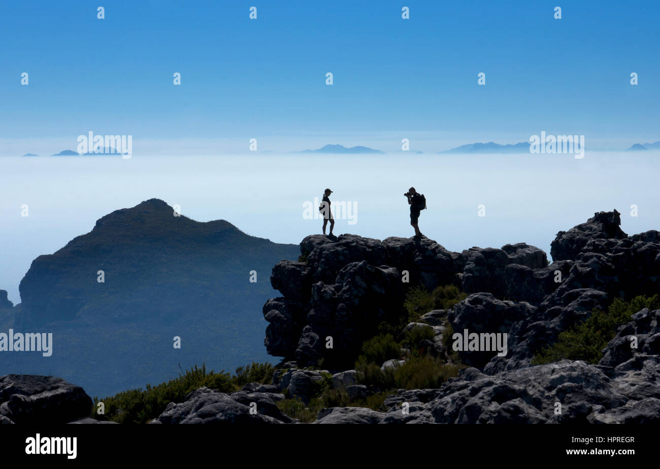 Tourists taking photographs of each other on top of Table mountain with dramatic early morning light,Cape town,South Africa Stock Photo