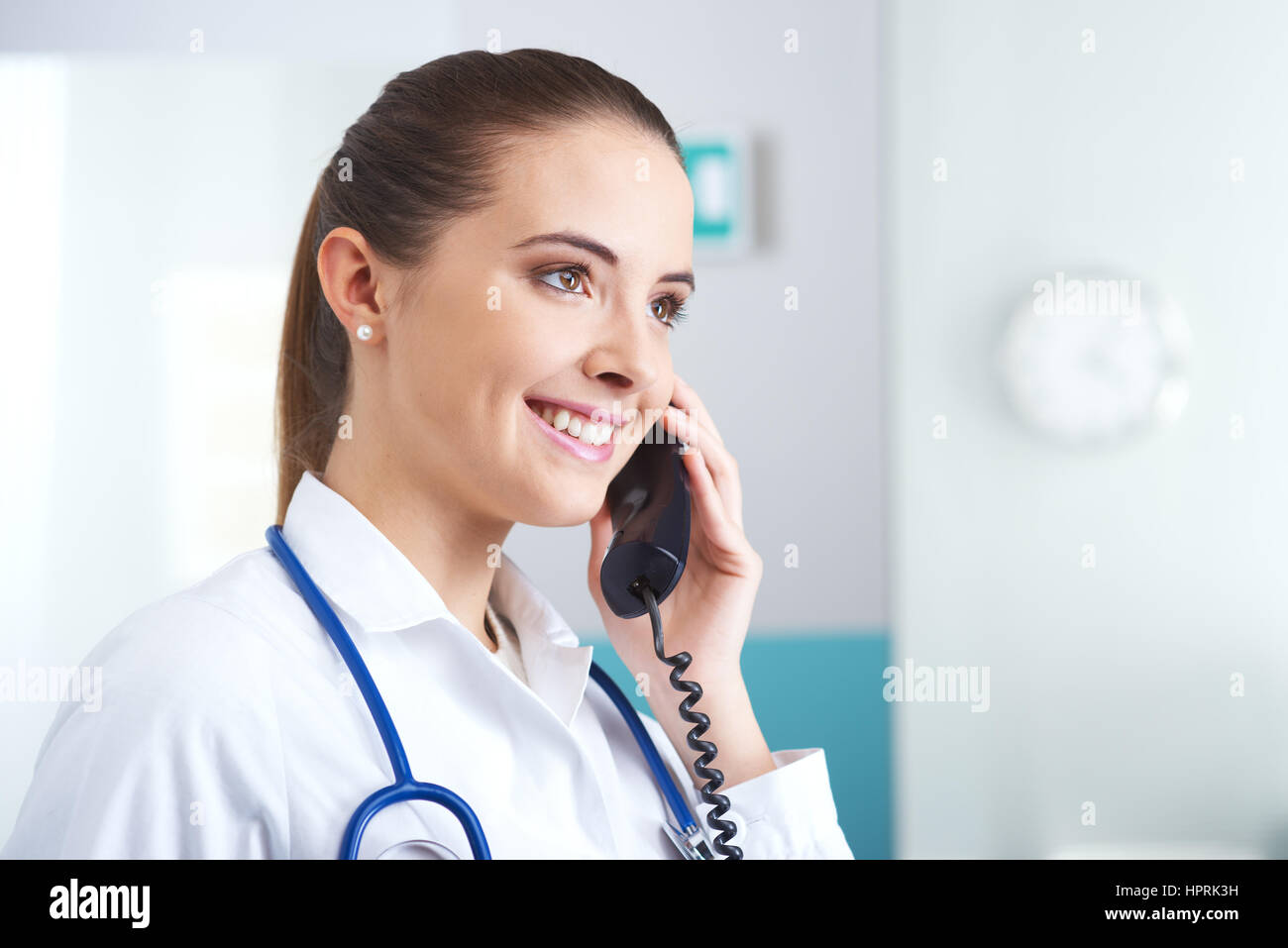 Young female doctor talking on the phone and smiling Stock Photo - Alamy