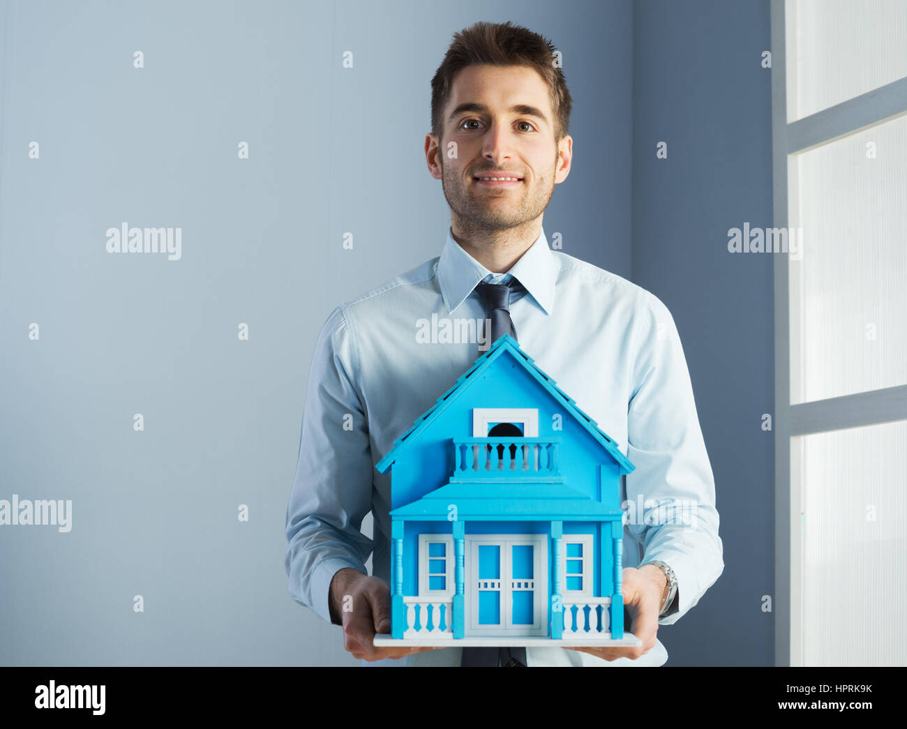 Friendly real estate agent with light blue model house. 