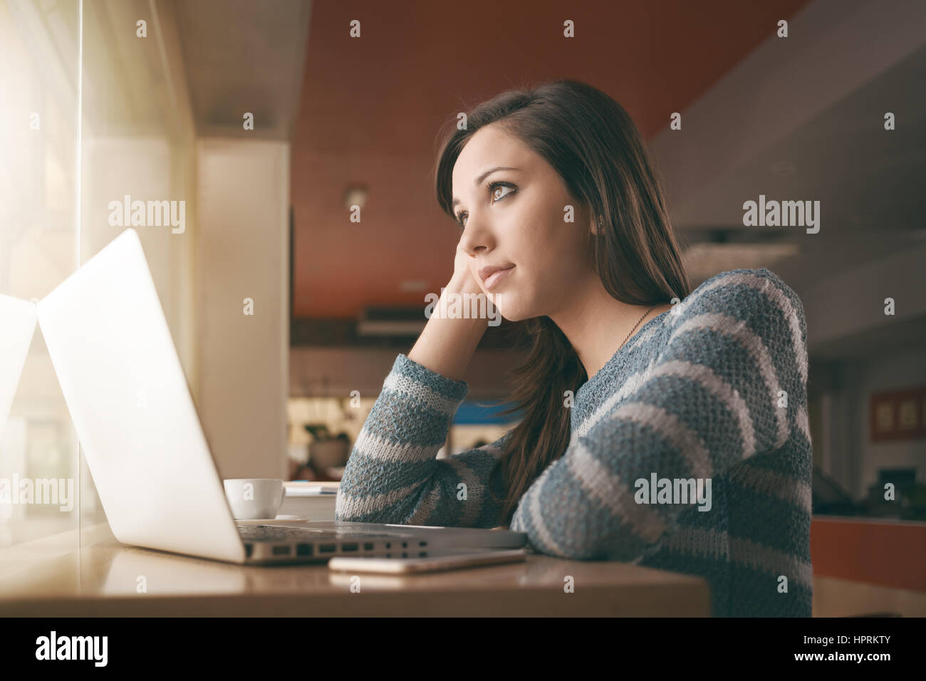 Teenager young girl using a laptop next to a window Stock Photo