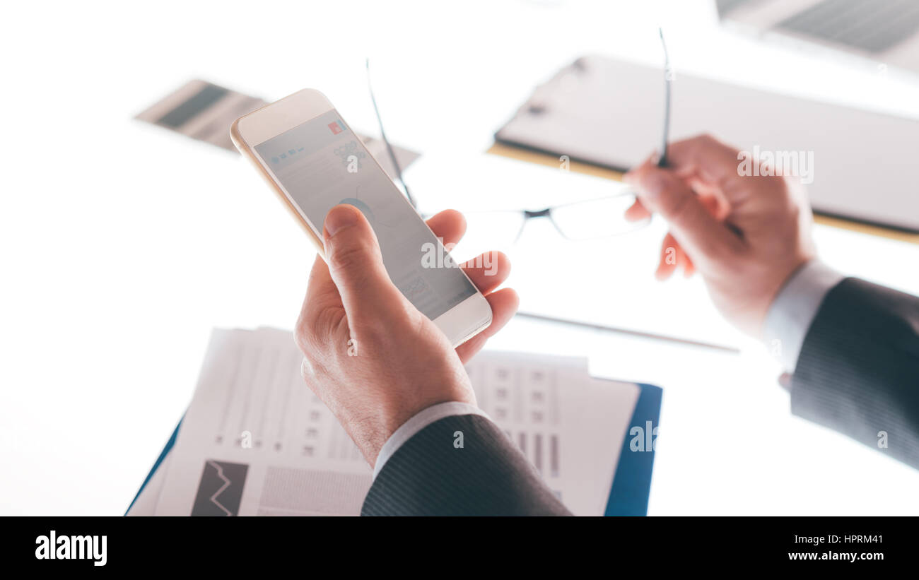 Businessman in his office using a mobile touch screen smartphone, hands ...