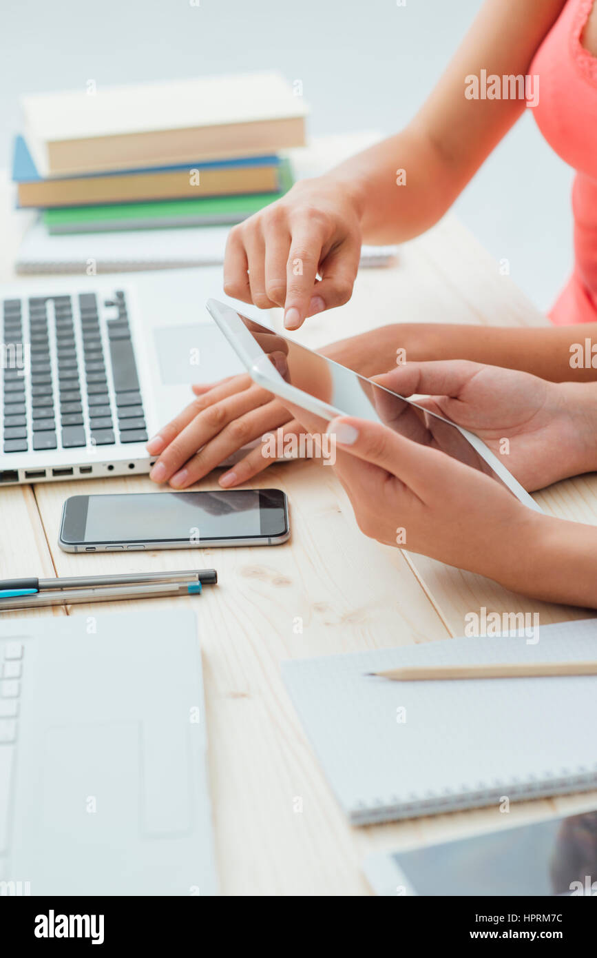 Student girls sitting at desk doing homeworks and using a digital ...