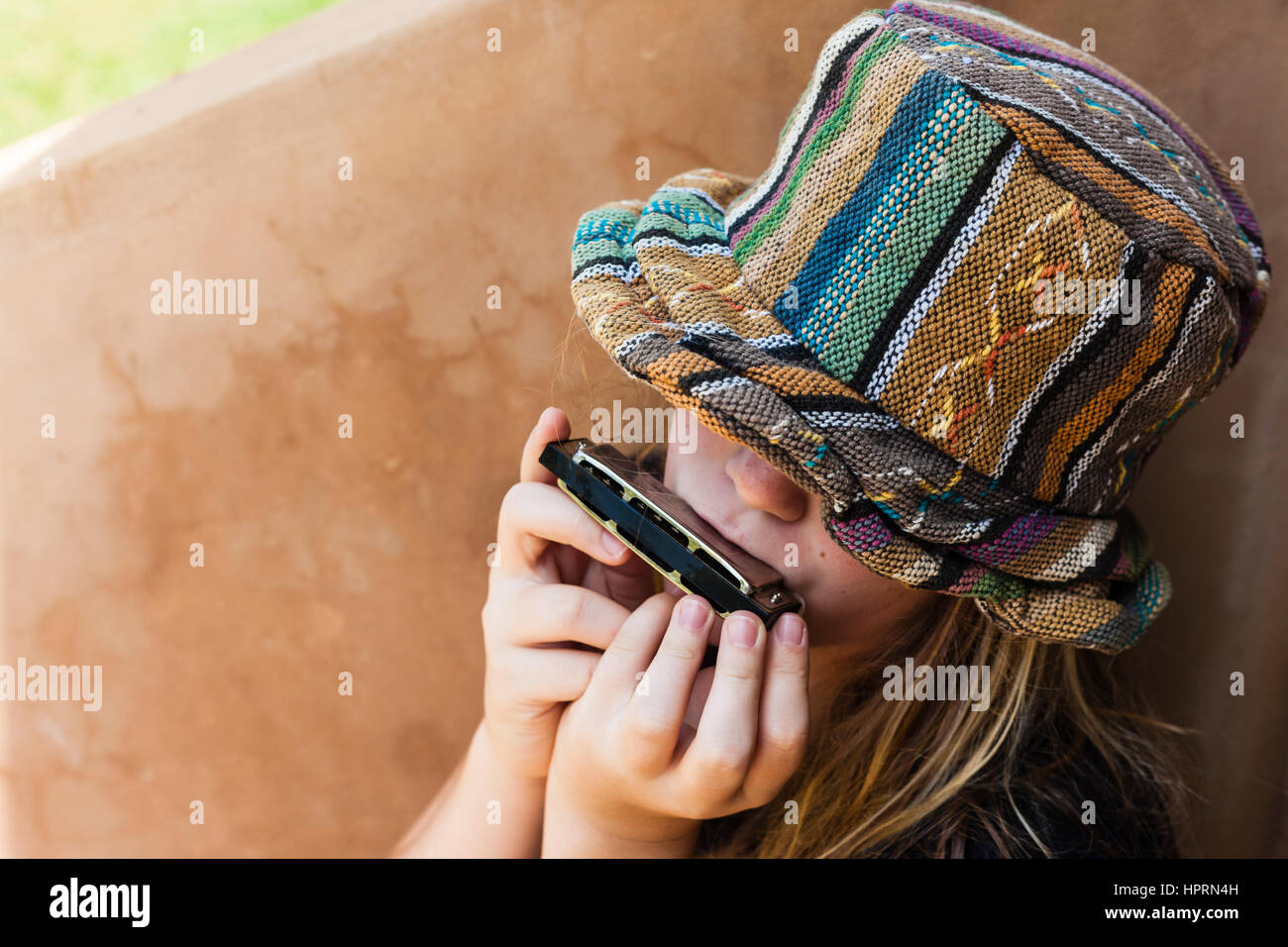 Girl wearing hat plays closeup unidentified playing mouth organ. Stock Photo