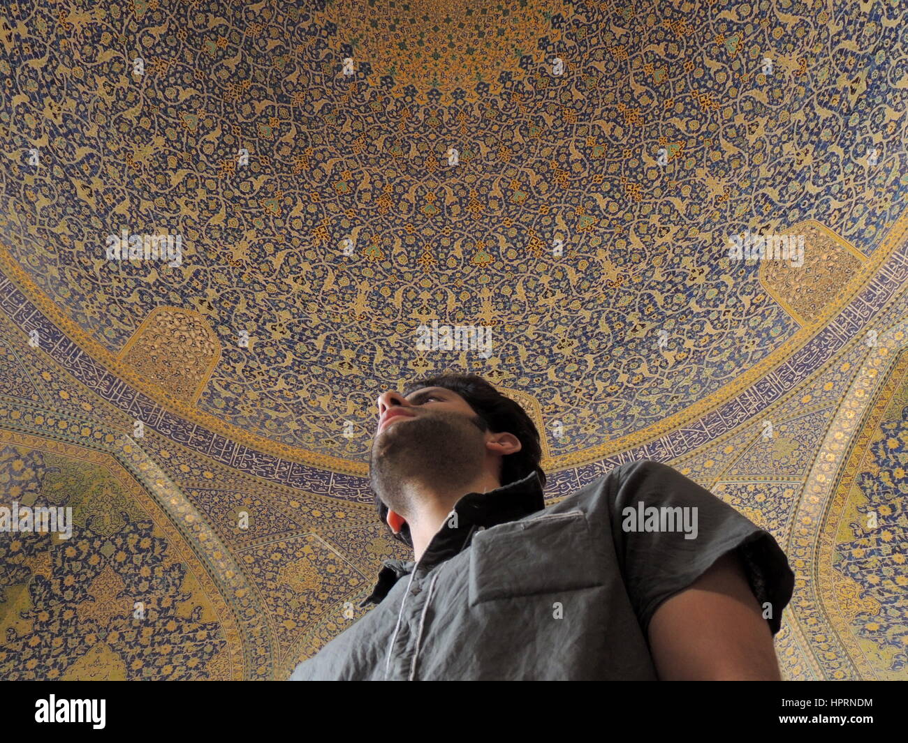 Young Iranian man sings under beautiful mosque dome using acoustics of echo chamber - Imam mosque, Isfahan, Iran Stock Photo