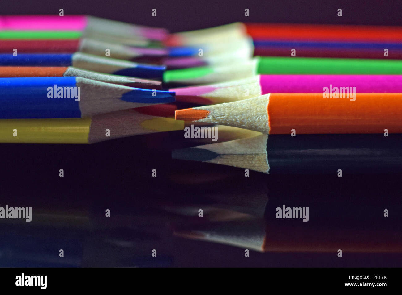 Close up of colored pencils on black reflective surface. Stock Photo