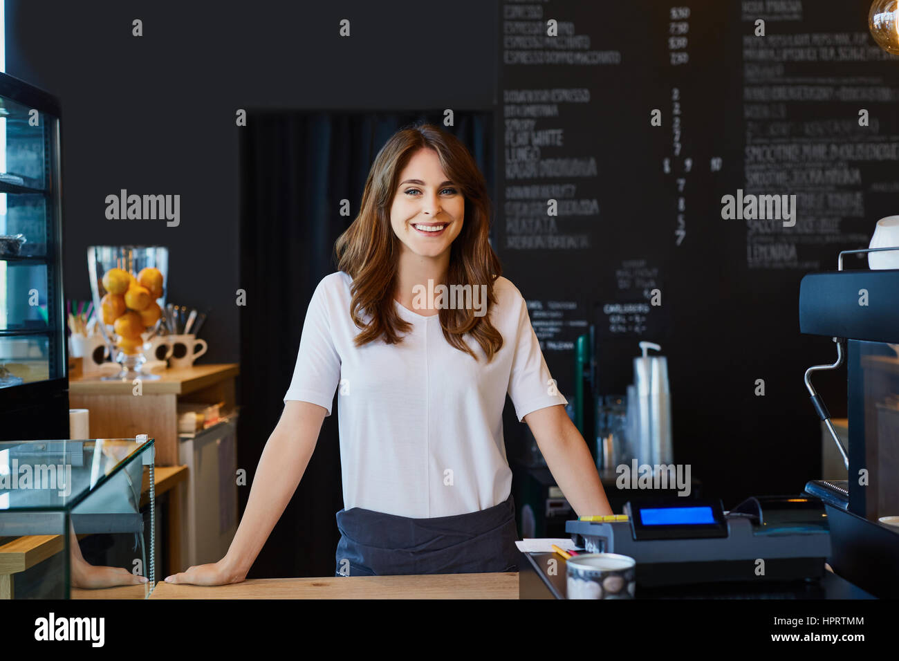 Beautiful female barista standing behind the bar in cafe Stock Photo