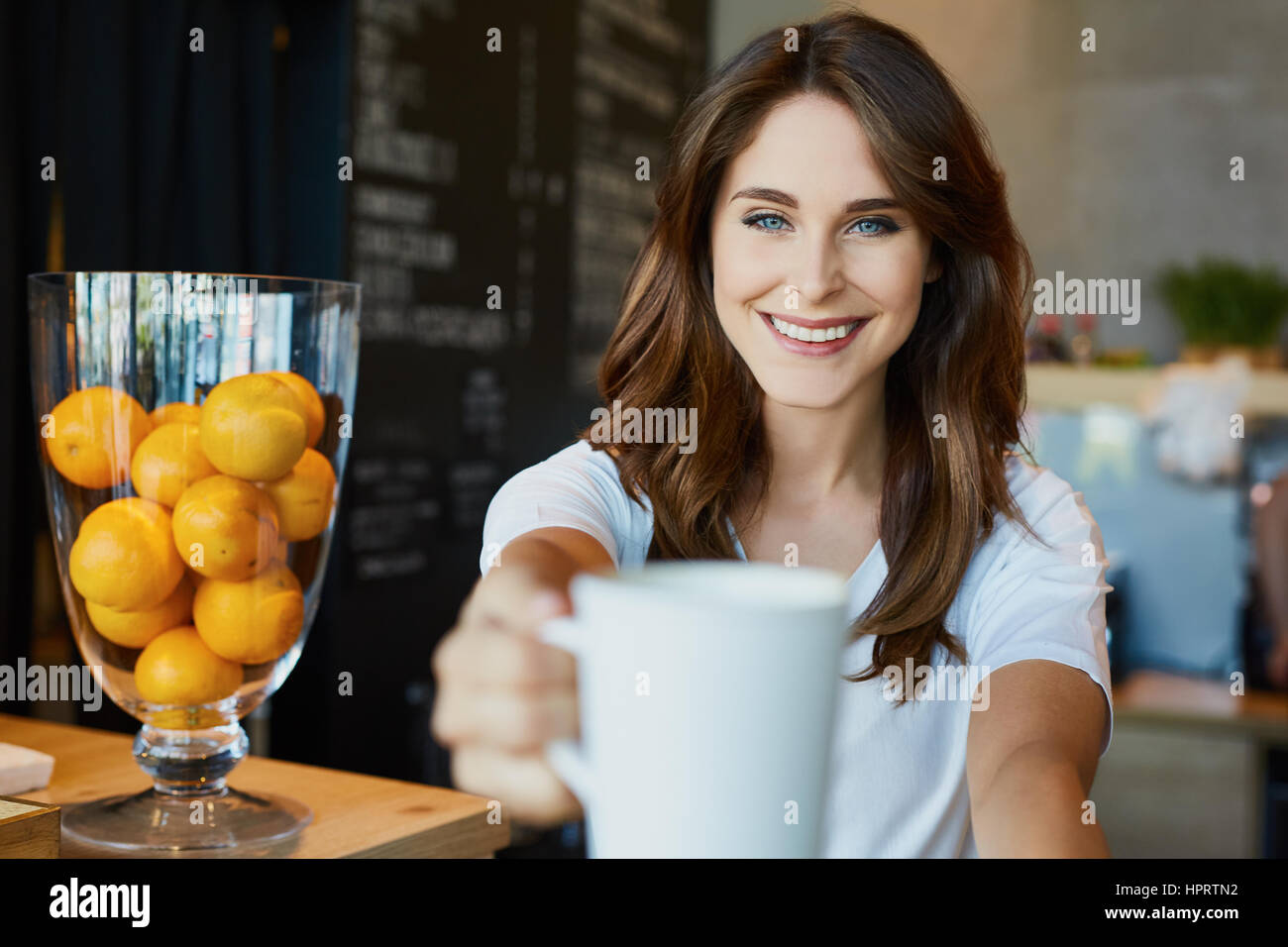 Happy, young woman serving coffee in cafe Stock Photo