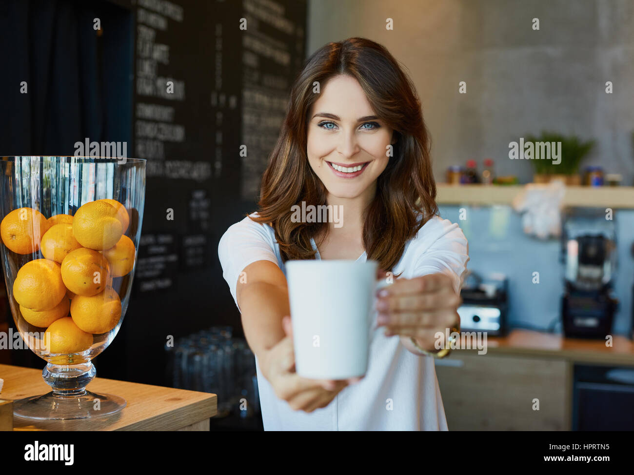 Young woman serving coffee in cafe Stock Photo