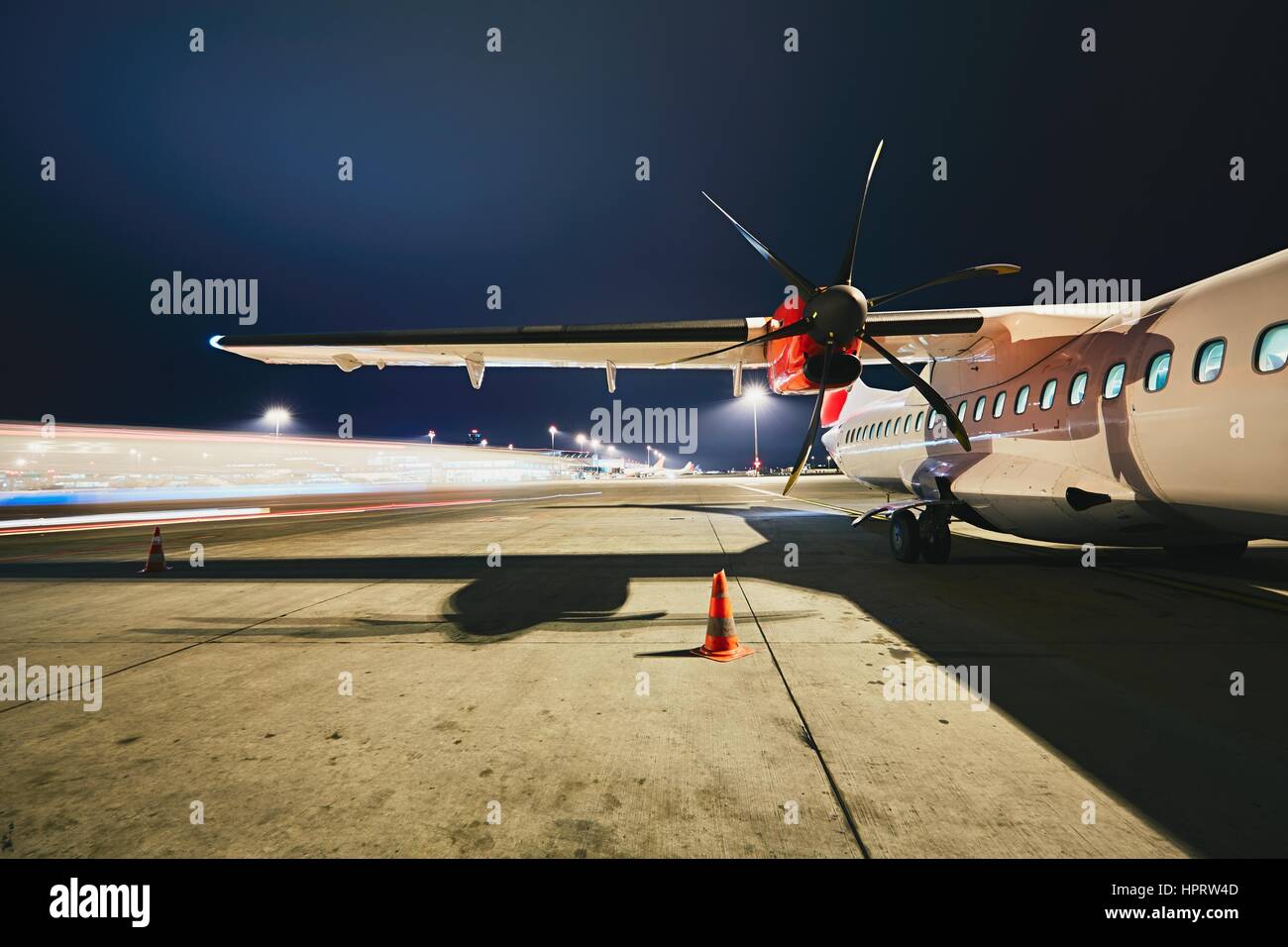 Busy airport in the night. Preparation of the turboprop airplane before flight. Stock Photo