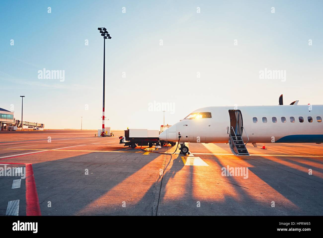 Daily life at the international airport. Preparation of the airplane at the sunset. Stock Photo