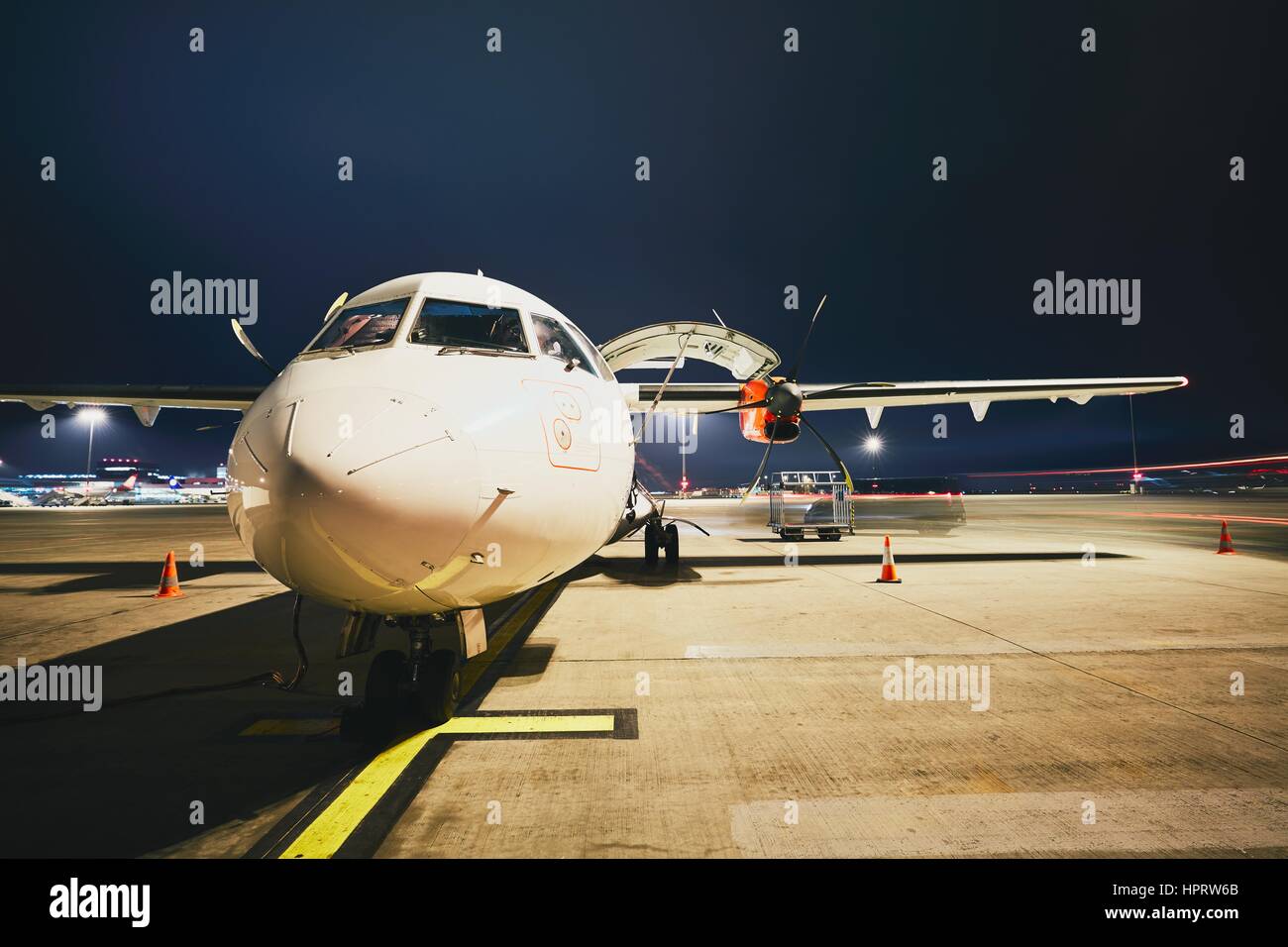 Busy airport in the night. Preparation of the turboprop airplane before flight. Stock Photo
